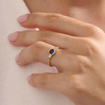 Model wearing a 14k gold anniversary ring with round sapphire and baguette moissanite stones. Sleek, timeless design for special occasions.