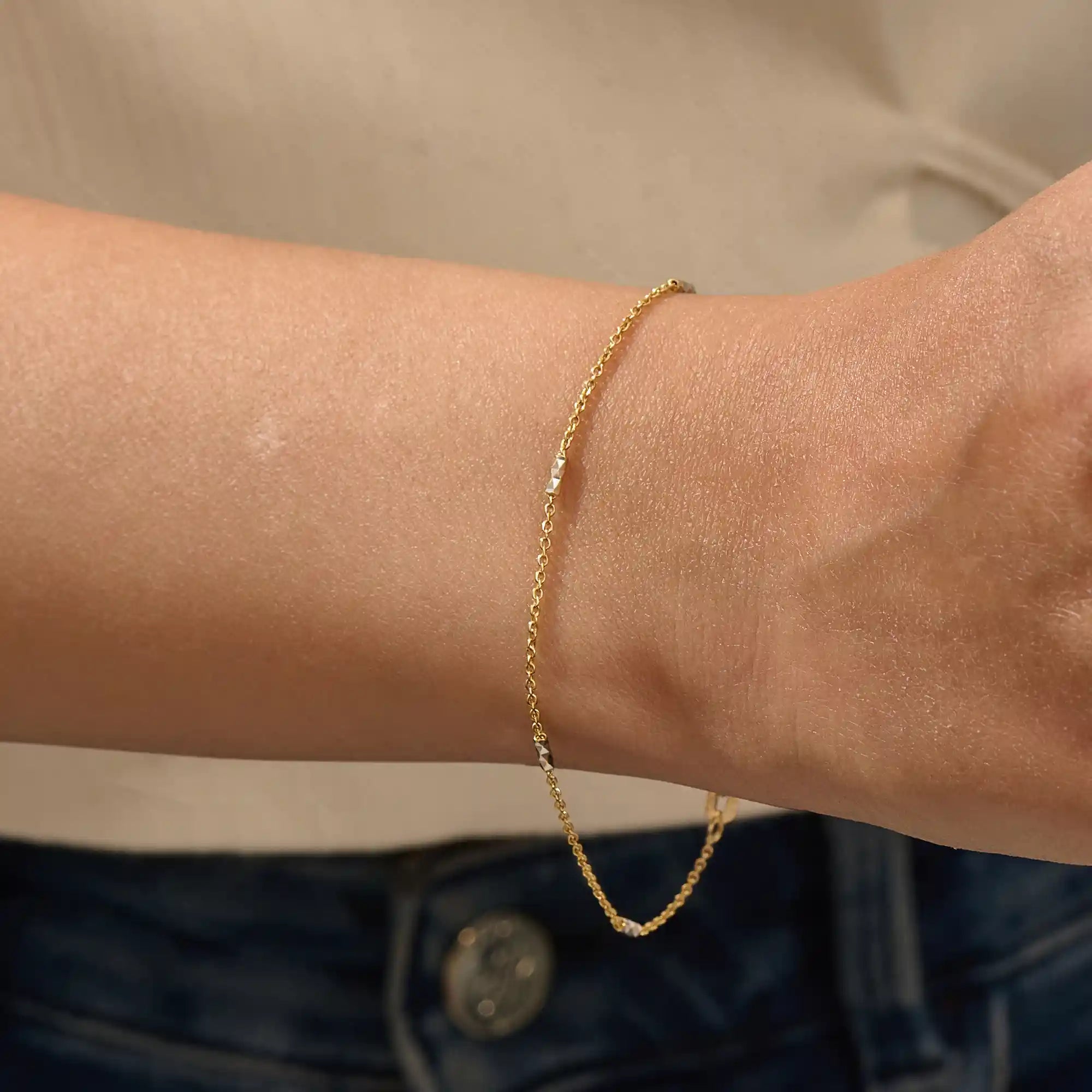 Model wearing a 14k gold bracelet with oval chain links and contrasting mixed-metal bar accents.