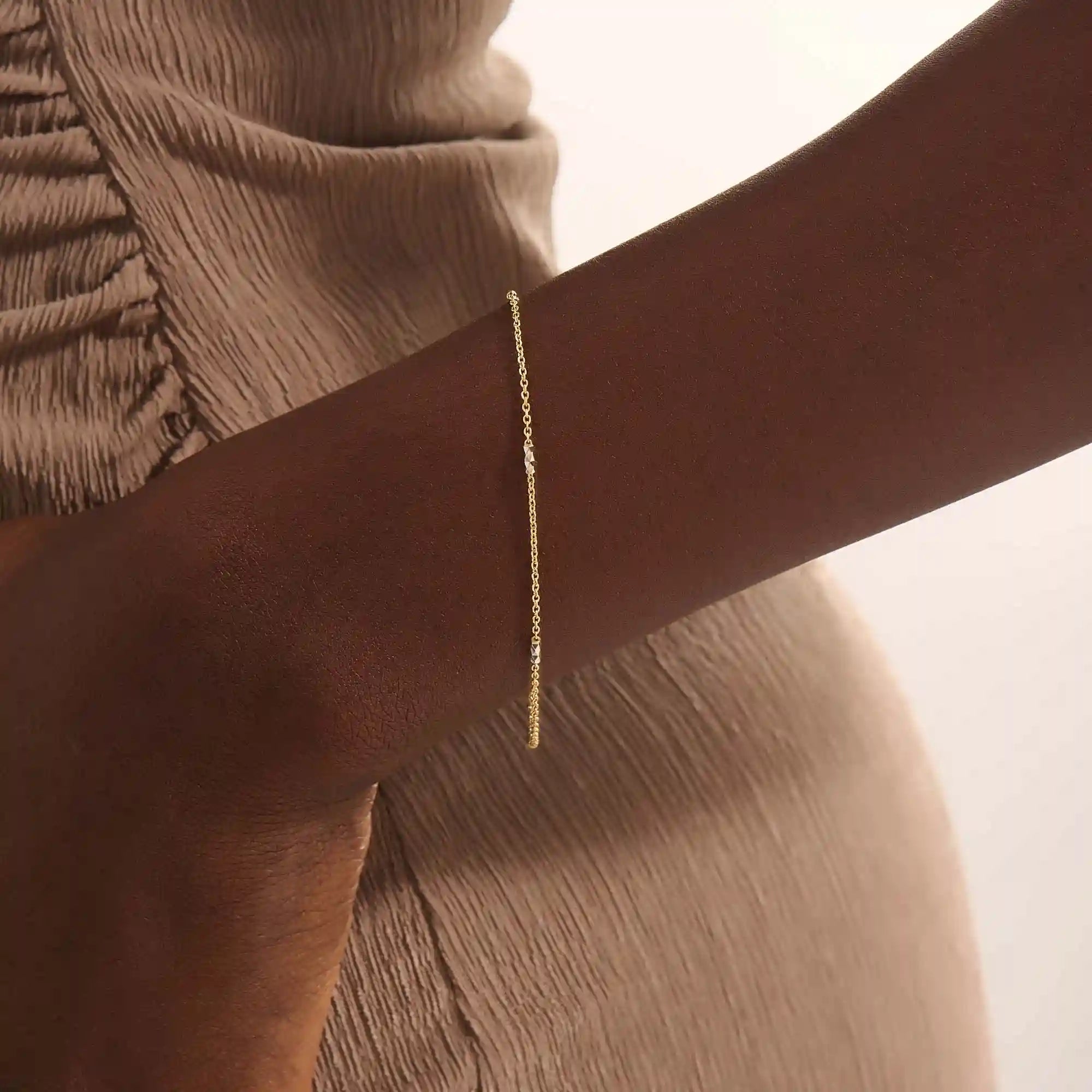Model wearing a 14k gold bracelet with oval chain links and contrasting mixed-metal bar accents.