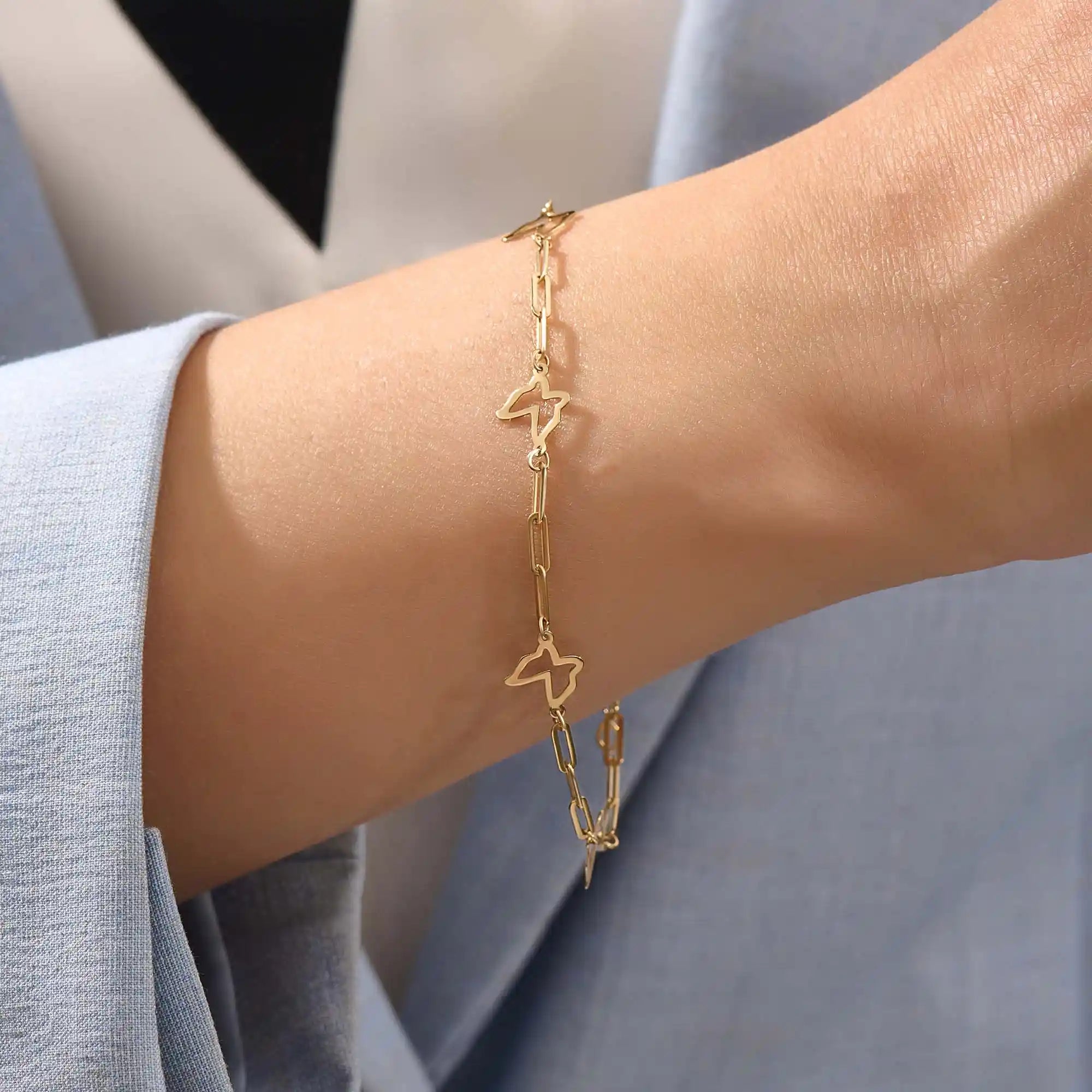 Model wearing a 14k gold butterfly bracelet with open butterfly charms and lightweight chain design.