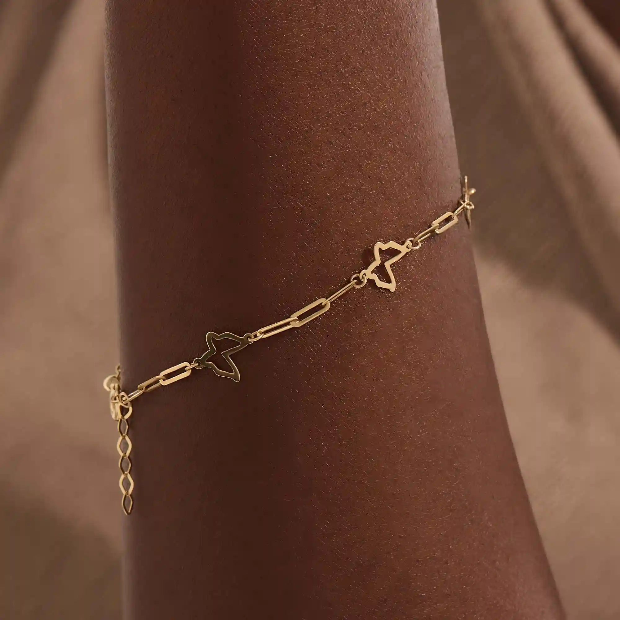Model wearing a 14k gold butterfly bracelet with open butterfly charms and lightweight chain design.