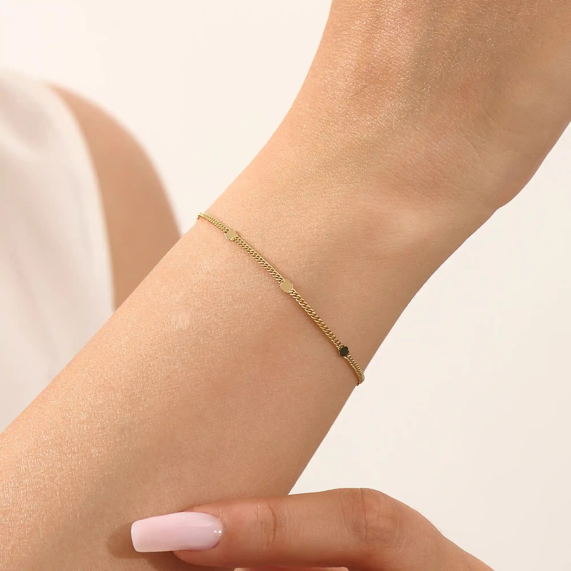 Model wearing a 14k gold chain bracelet with curb links and disc accents, modern and stylish.