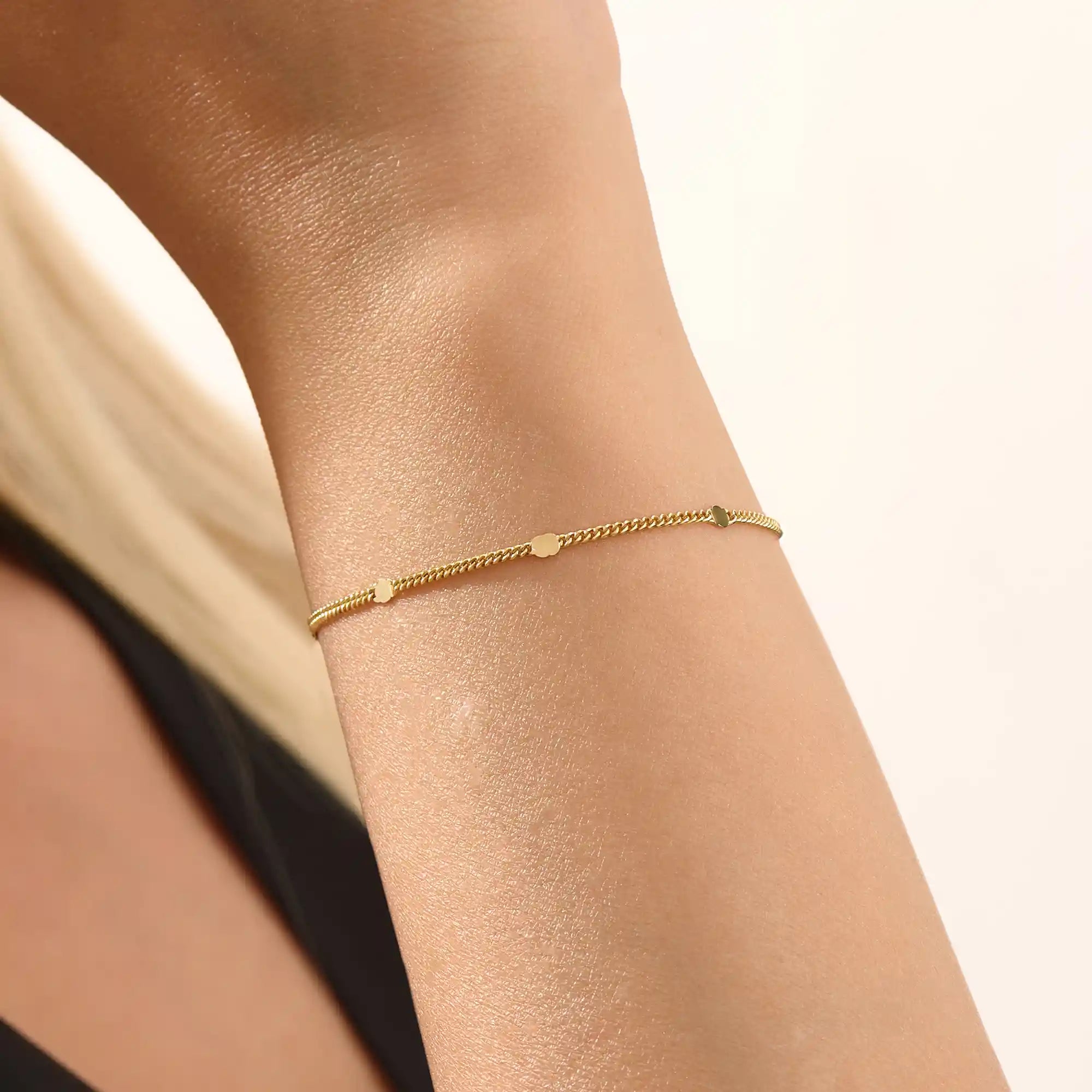Model wearing a 14k gold chain bracelet with curb links and disc accents, modern and stylish.