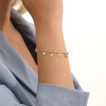 Model wearing a 14k gold dangling star bracelet with hanging charms, adding a whimsical and elegant touch.