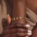 Model wearing a 14k gold dangling star bracelet with hanging charms, adding a whimsical and elegant touch.