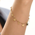 Model wearing a 14k gold dangling star bracelet with hanging charms, adding a whimsical and elegant touch.