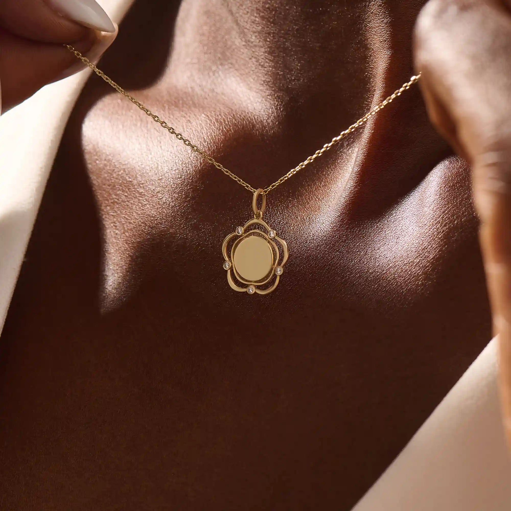 Model wearing a 14k gold flower pendant necklace with an engravable plain surface. A delicate and personalized accessory ideal for daily wear.