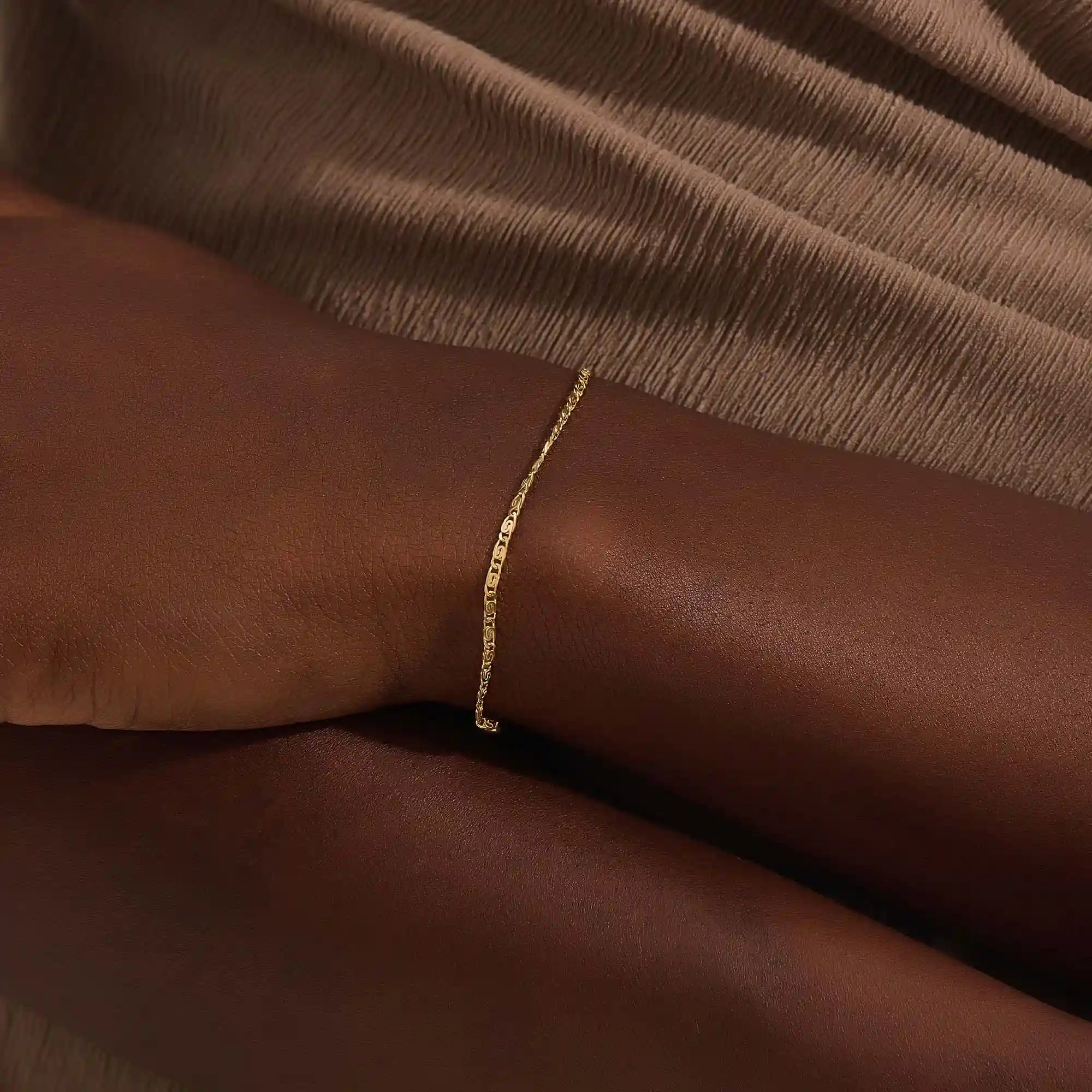 Model wearing a 14k gold scroll chain bracelet, showcasing the slim rectangular scroll link design on the wrist.