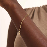 Model wearing a 14k gold textured chain bracelet, elegant with shimmering starburst accents.