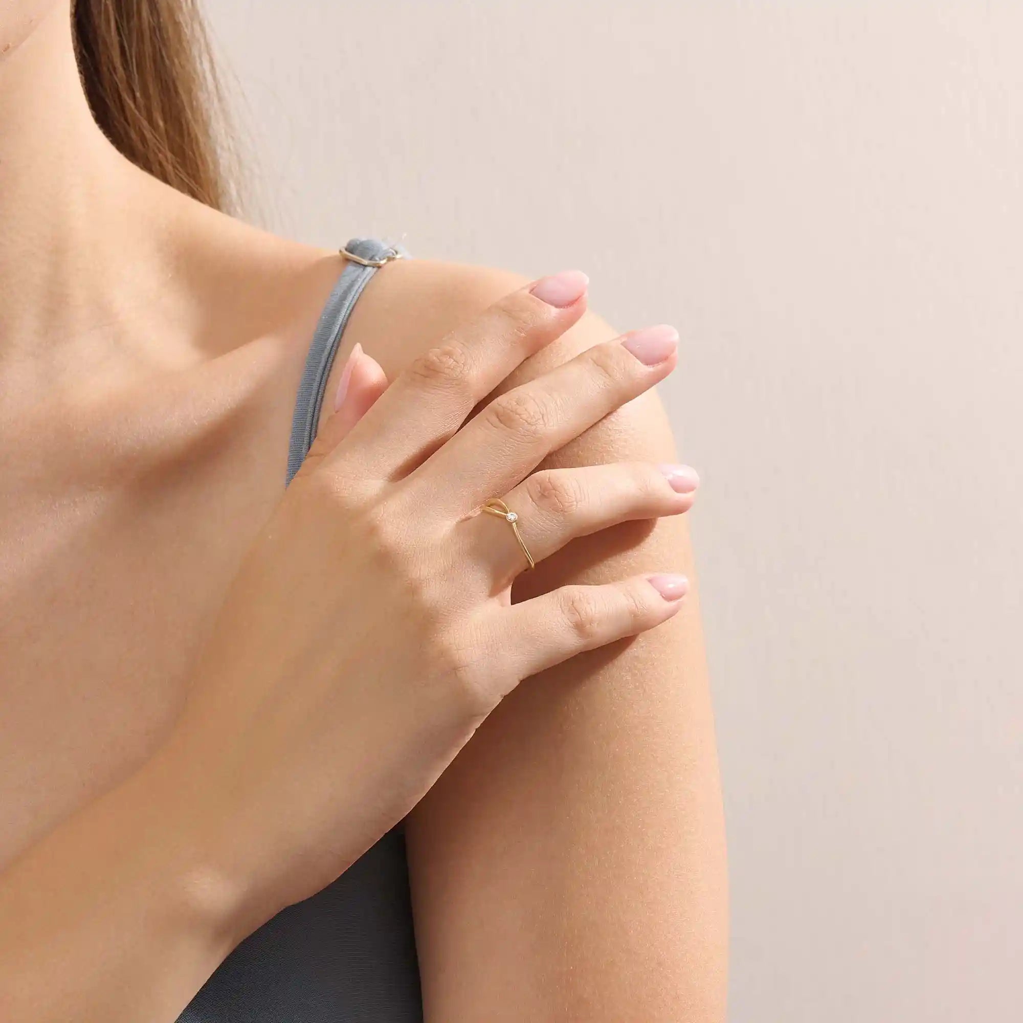 Model wearing a 14k solid gold split band promise ring with a delicate moissanite accent, showcasing a sleek and contemporary minimalist style.