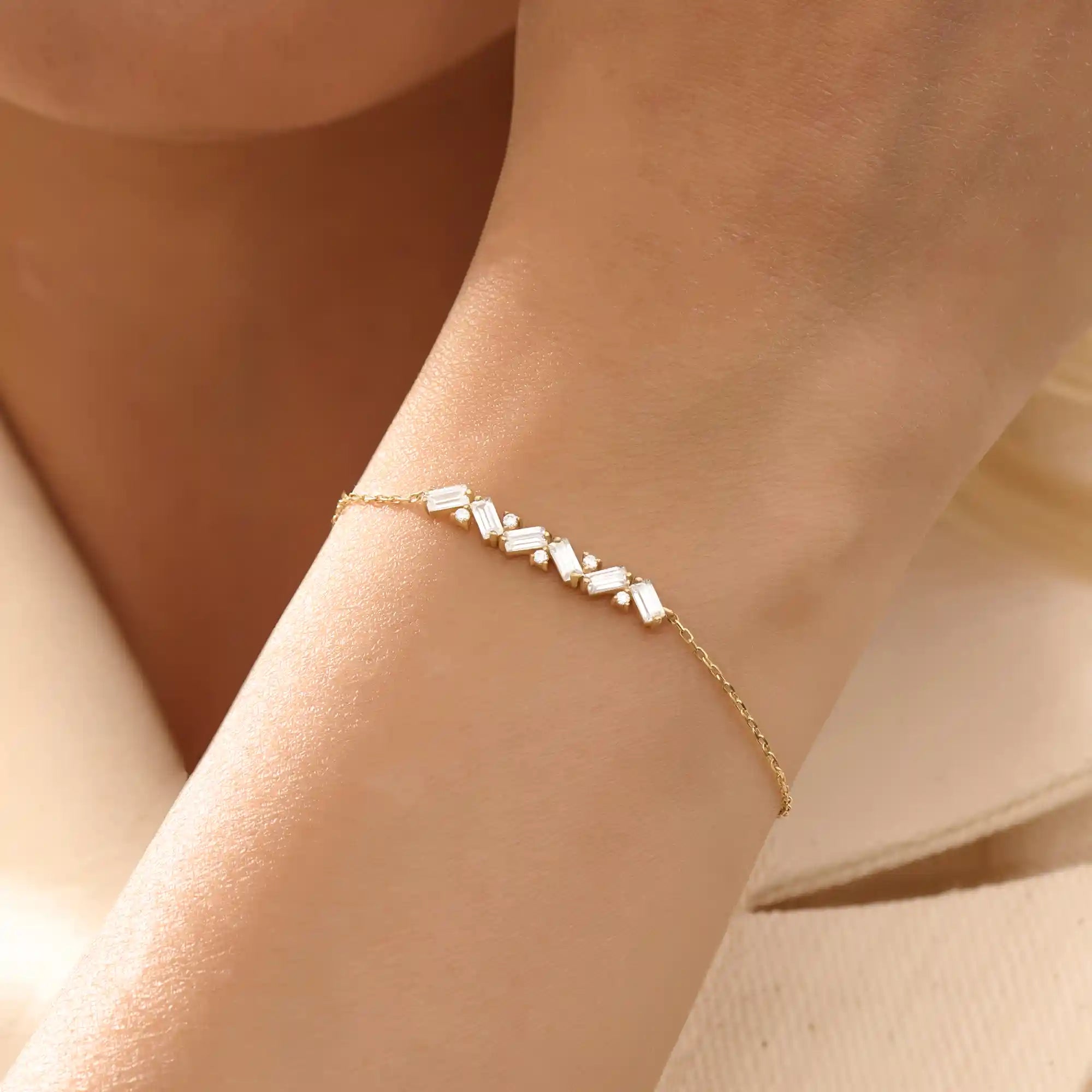 Model wearing a 14k yellow gold baguette bar bracelet with baguette-cut and round stones, adding sparkle to a refined wrist look.