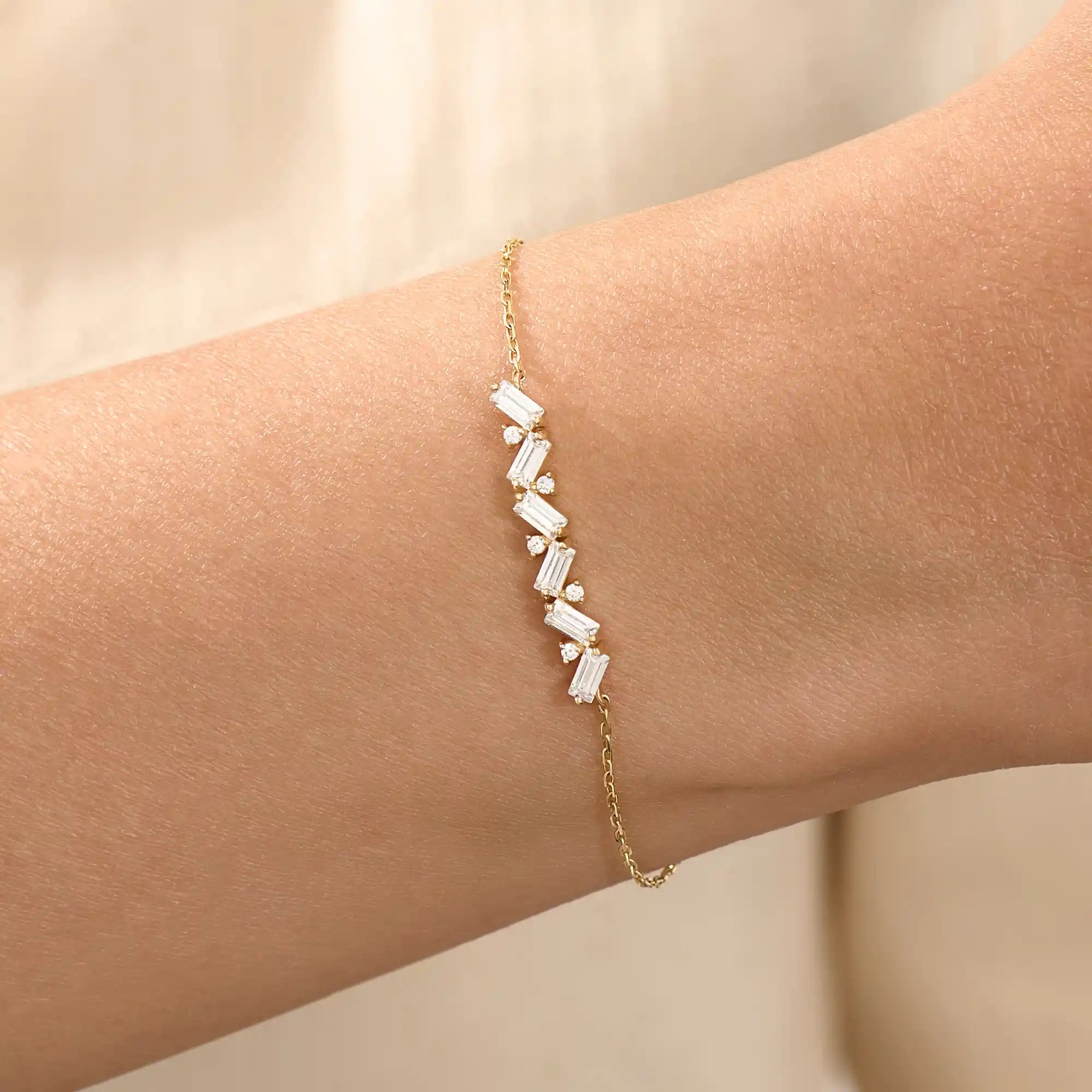 Model wearing a 14k yellow gold baguette bar bracelet with baguette-cut and round stones, adding sparkle to a refined wrist look.