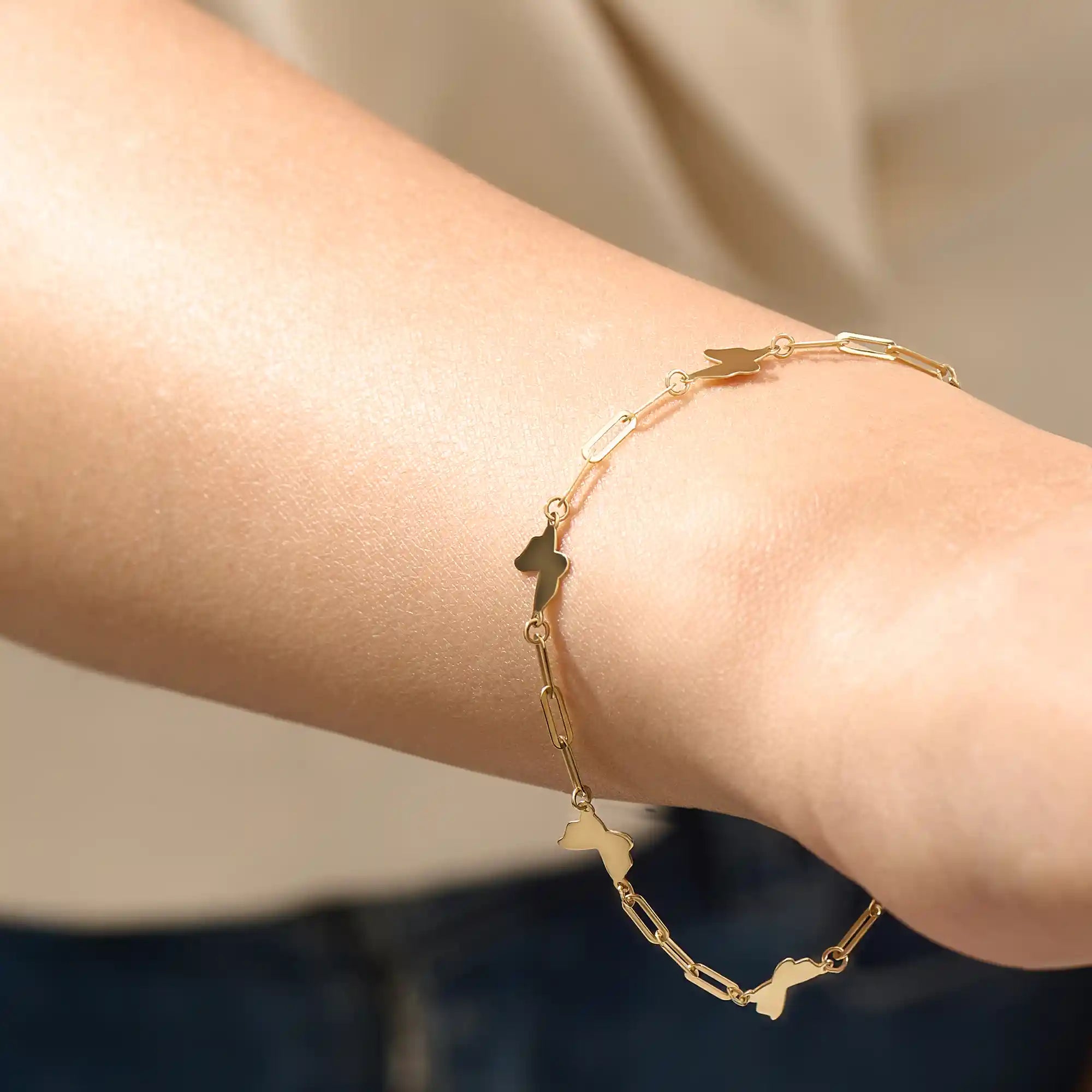 Model wearing a 14k yellow gold butterfly chain bracelet with polished butterfly charms and delicate chain details.