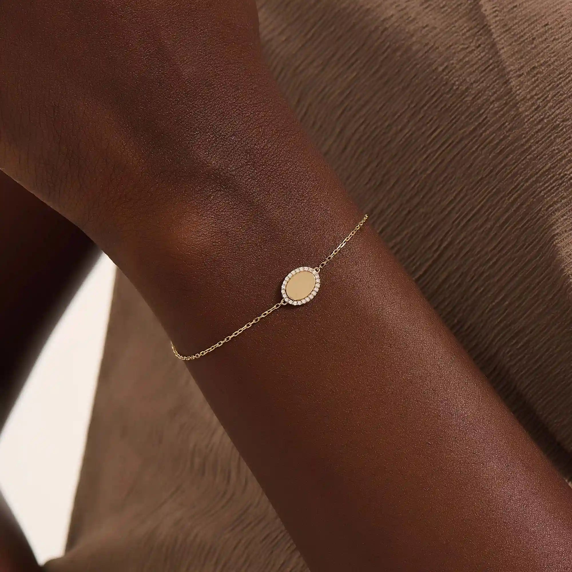 Model wearing a 14k yellow gold oval bracelet with pavé moissanite halo, adding refined sparkle to the wrist.