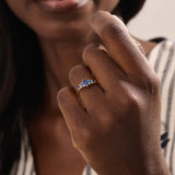 Model wearing a 5 pear sapphire gold ring on hand. Classic anniversary ring with vivid blue sapphires in 14k solid gold.