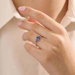 Model wearing a 5 pear sapphire gold ring on hand. Classic anniversary ring with vivid blue sapphires in 14k solid gold.