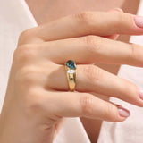 Model wearing a bold Toi et Moi ring with pear topaz and oval moissanite on a thick gold dome band.