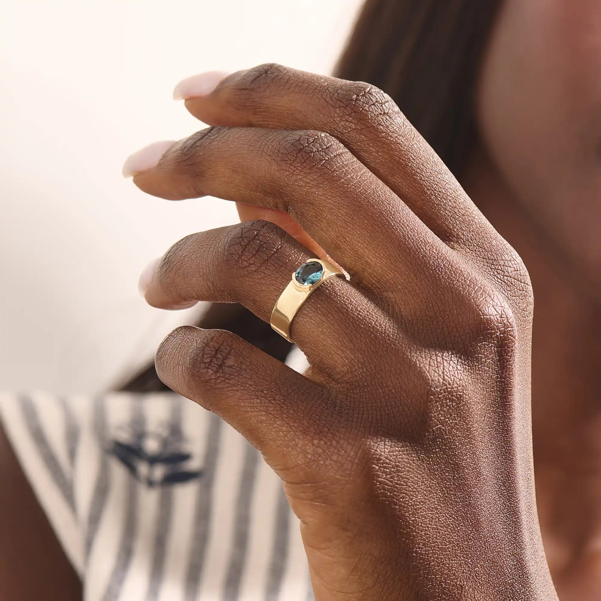 Model wearing a chunky 14k gold ring with half bezel set oval topaz. A statement gemstone ring with modern lines. Ideal for daily elegance or gifting.