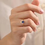 Model wearing a pear-shaped sapphire ring with moissanite accents in solid gold. A refined gemstone ring for special occasions or daily elegance.