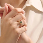 Model wearing a pear cut moss agate ring in 14k gold. A one-of-a-kind vintage anniversary ring with earthy elegance.