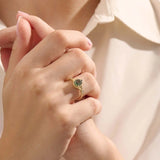 Model wearing a pear cut moss agate ring in 14k gold. A one-of-a-kind vintage anniversary ring with earthy elegance.