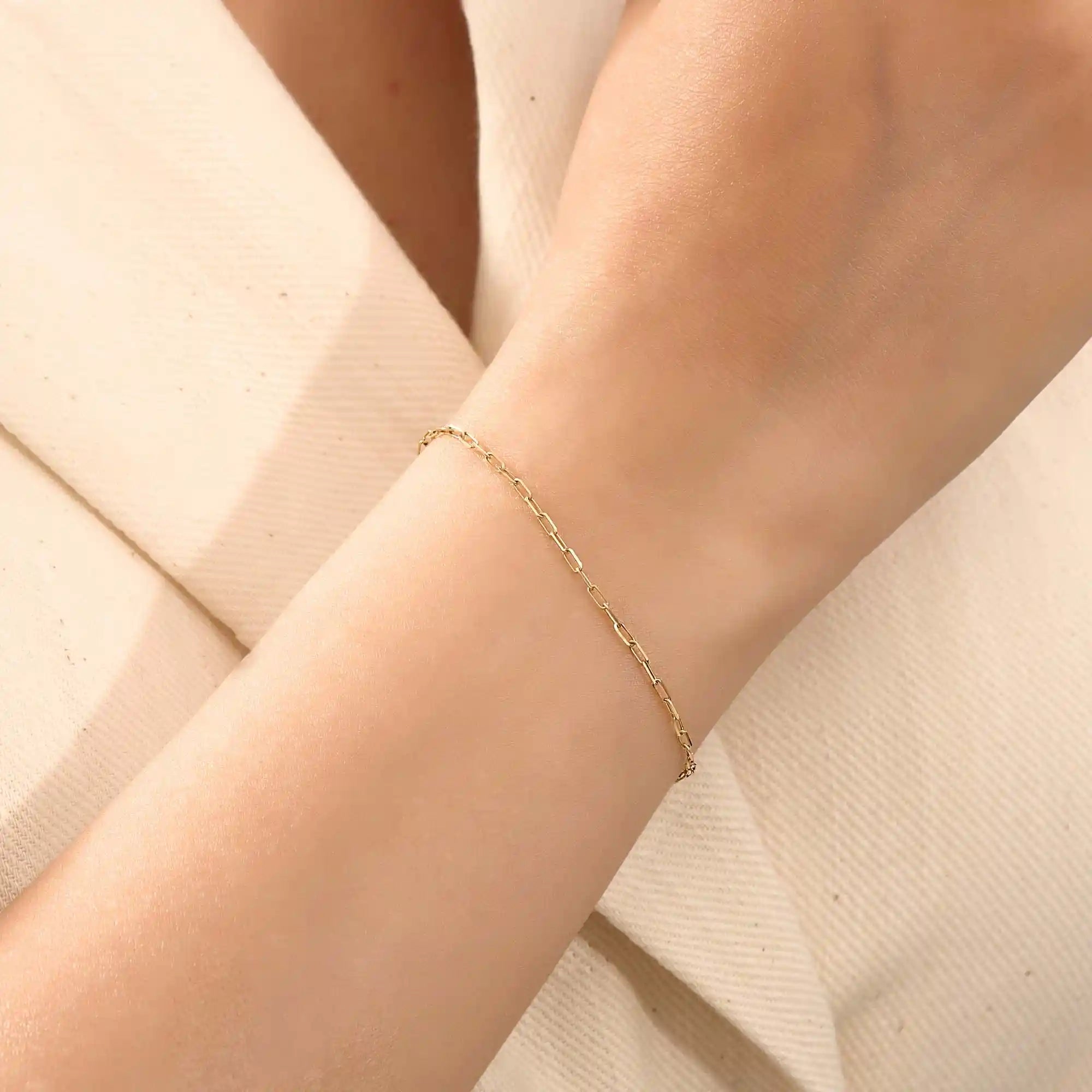 Model wearing a slim 14k gold link chain bracelet with elongated links, styled for everyday wear.