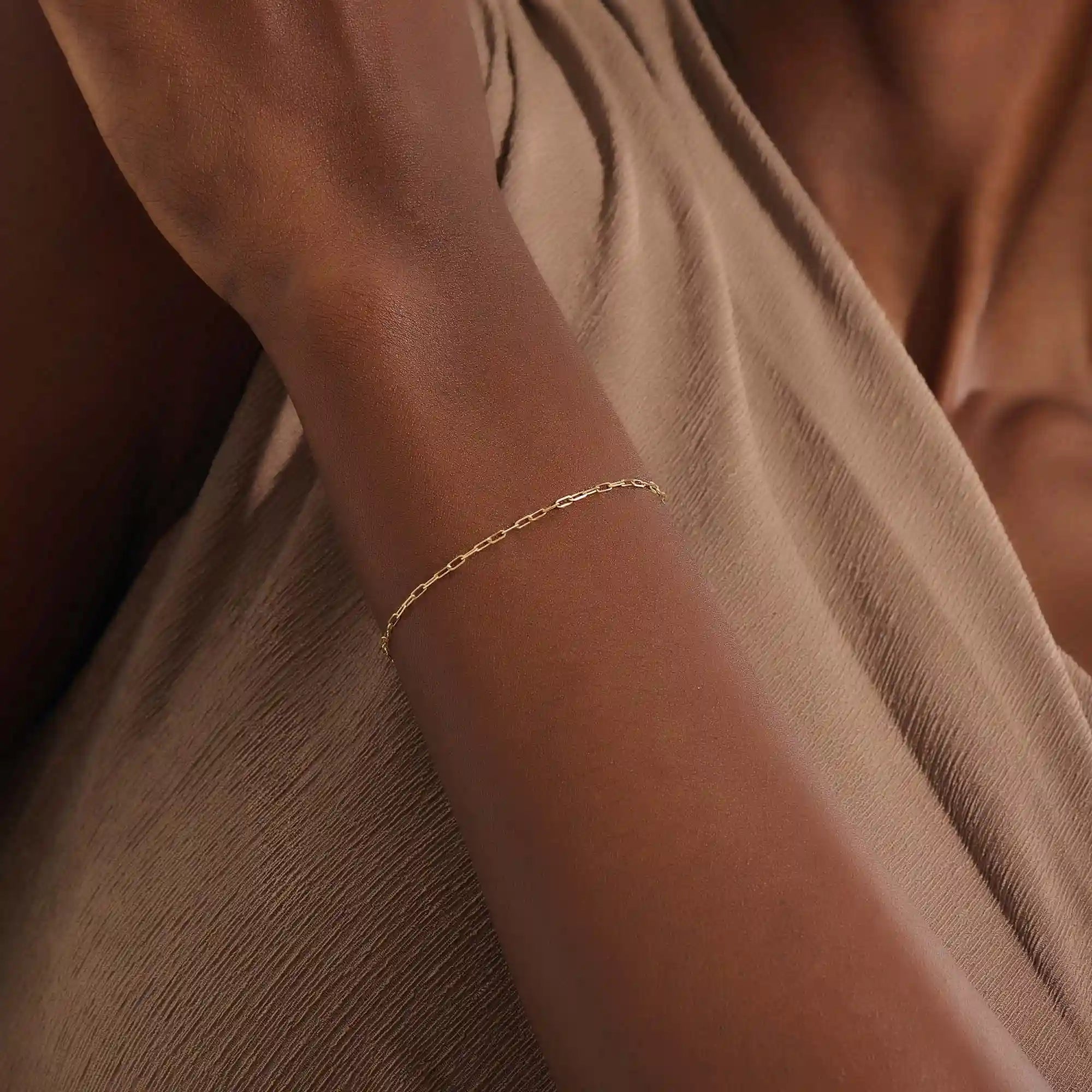 Model wearing a slim 14k gold link chain bracelet with elongated links, styled for everyday wear.