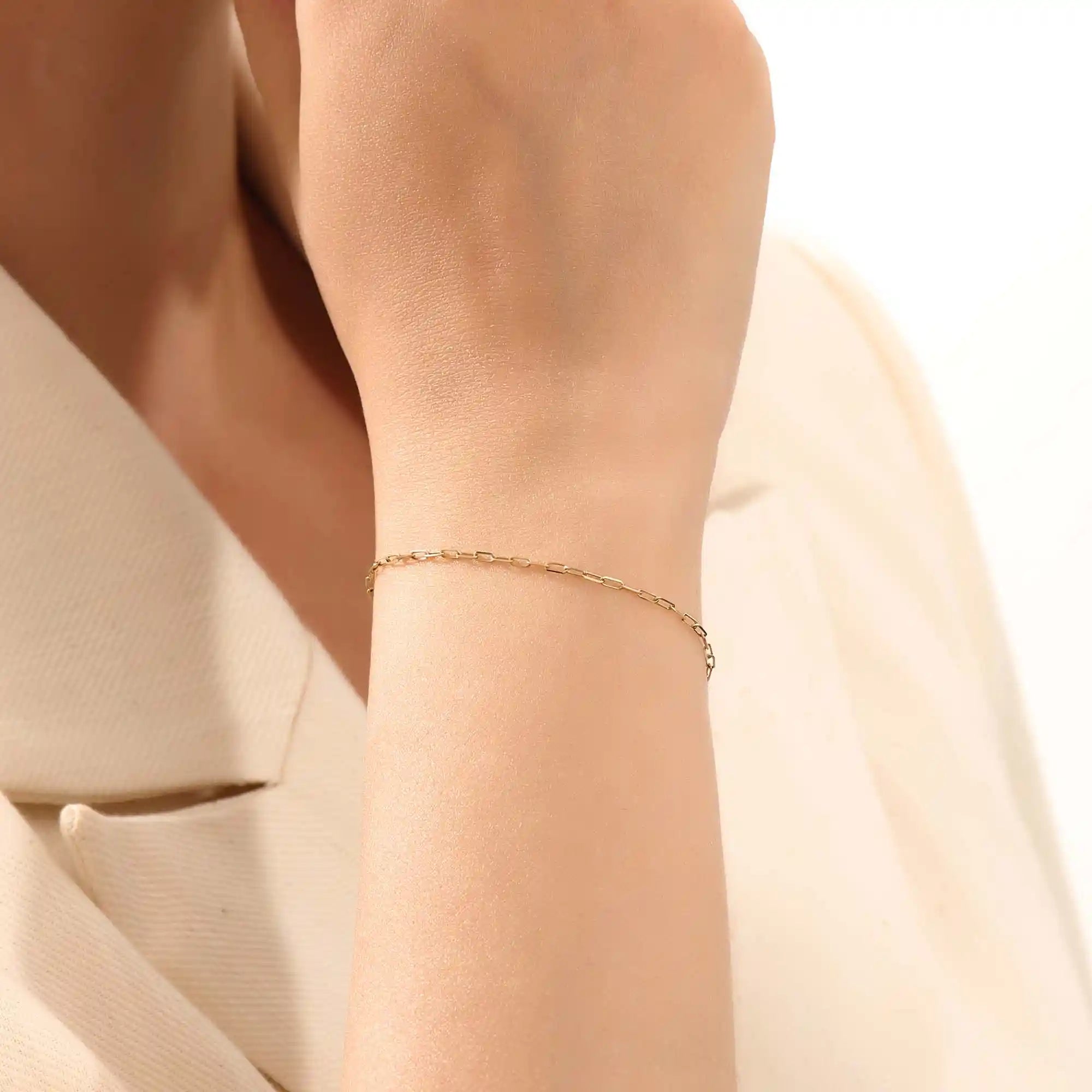 Model wearing a slim 14k gold link chain bracelet with elongated links, styled for everyday wear.