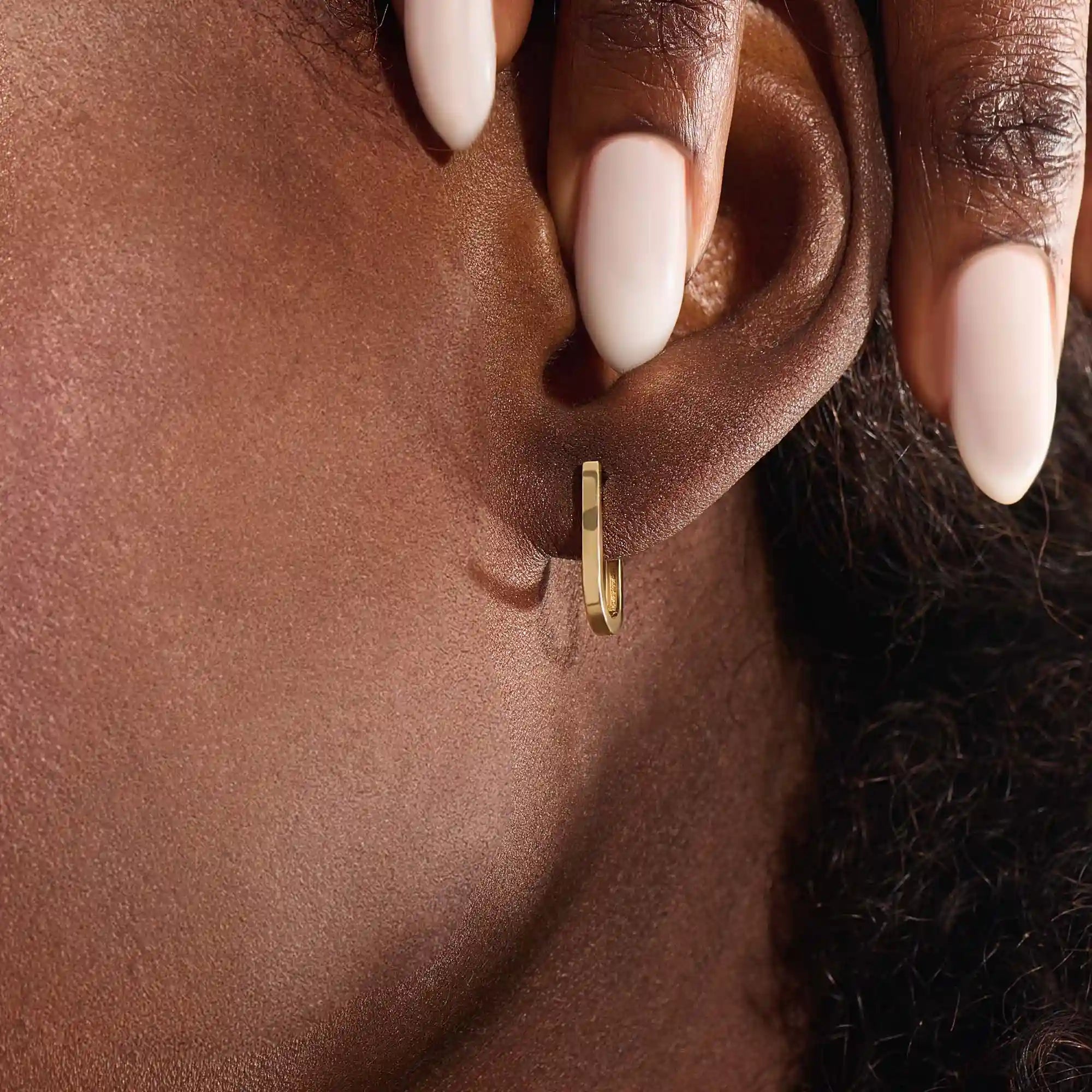 Model wearing minimalist U-shape hoop earrings in 14k gold, highlighting the sleek geometric design.