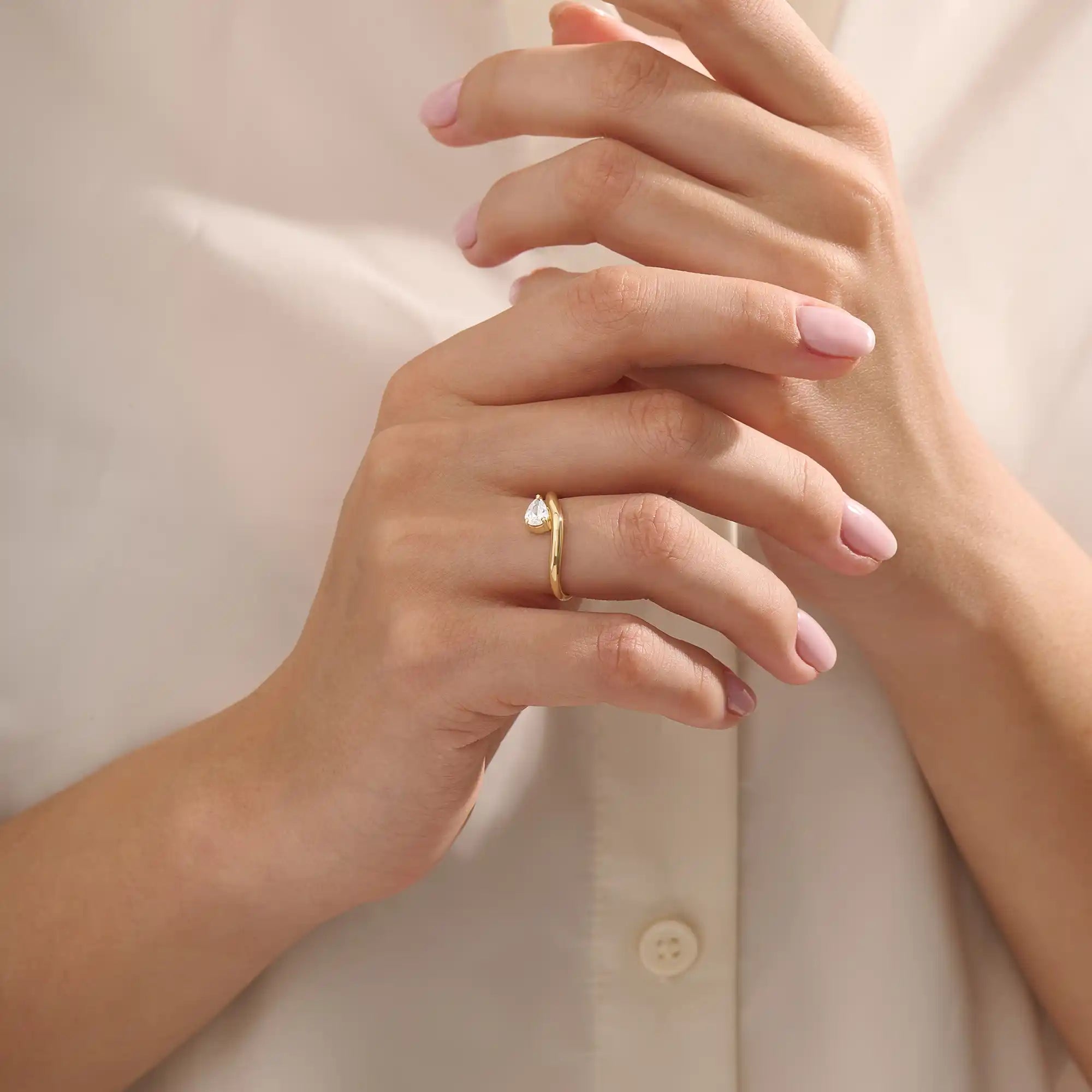 Model wearing pear cut moissanite solitaire engagement ring on a curved 14k solid gold band, highlighting its sleek and modern minimalist style.