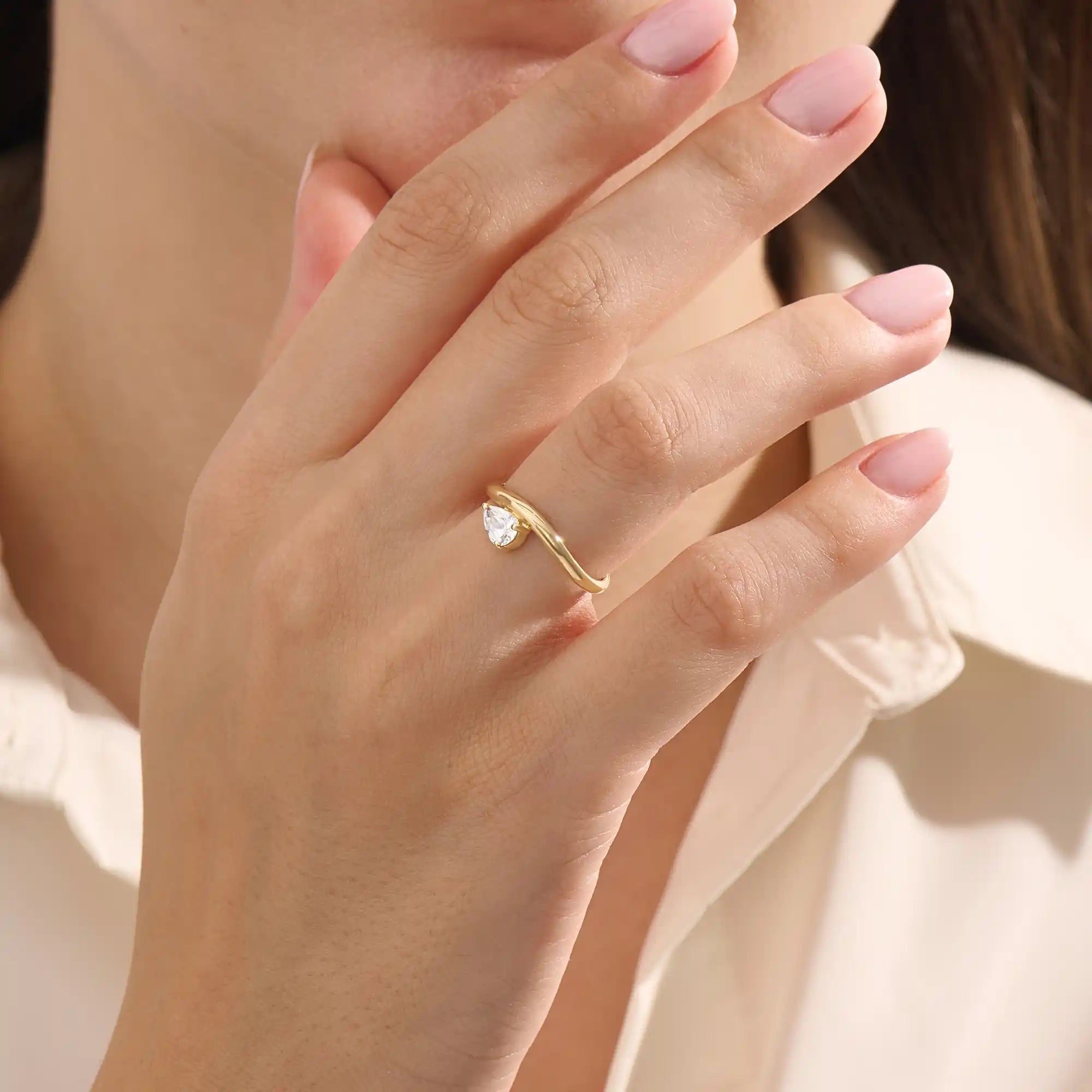 Model wearing pear cut moissanite solitaire engagement ring on a curved 14k solid gold band, highlighting its sleek and modern minimalist style.