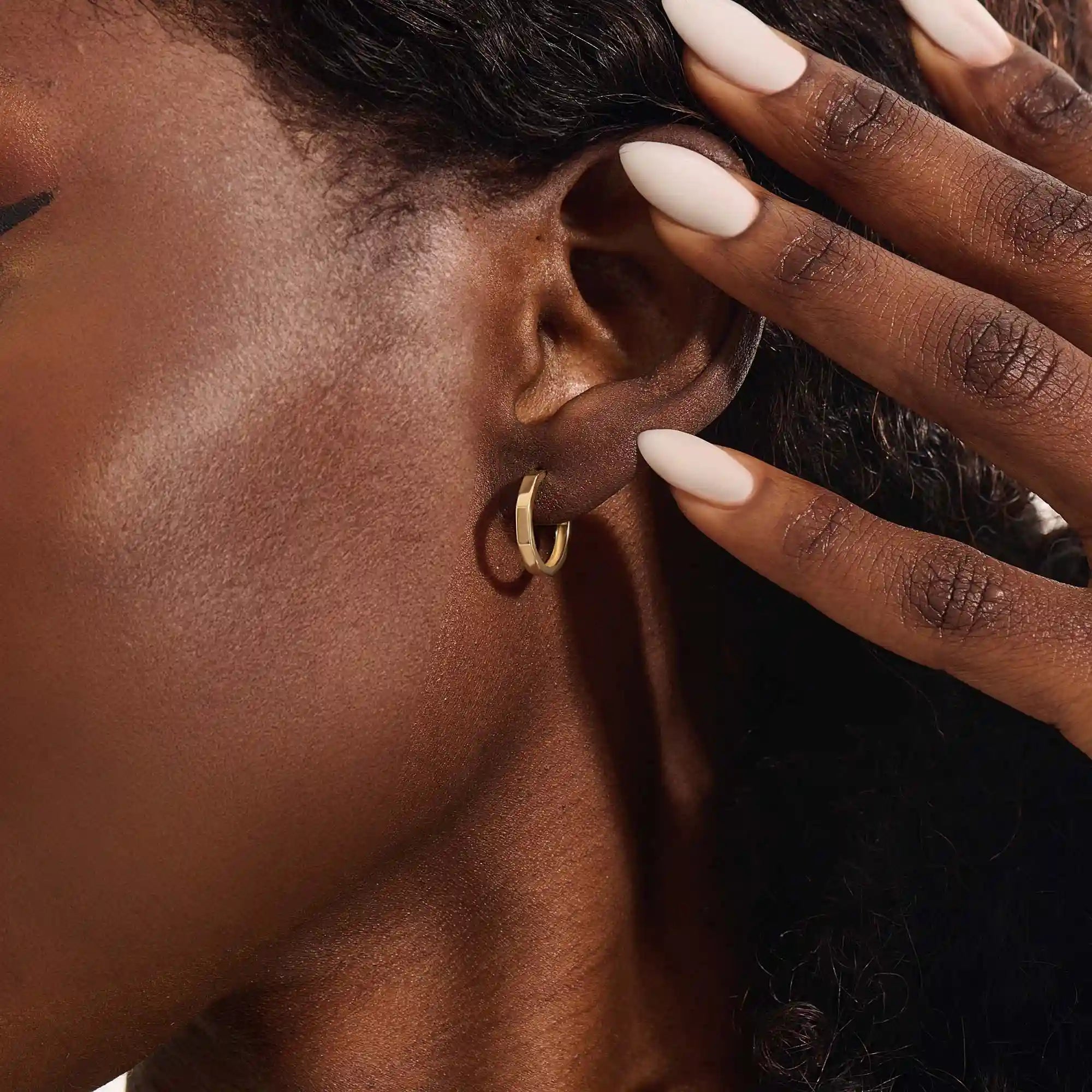 Model wearing small minimal hoop earrings in 14k gold, highlighting their modern minimal style.