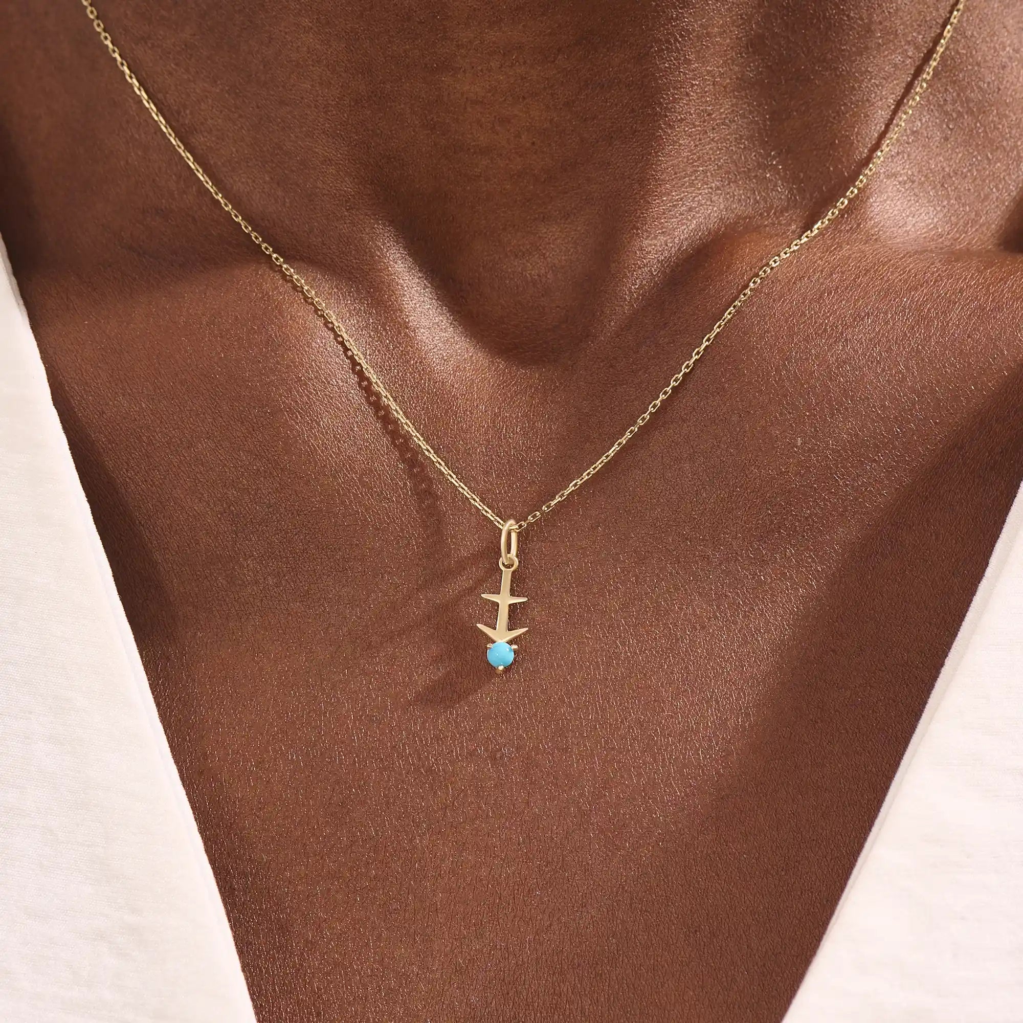 Model wears Sagittarius zodiac symbol pendant necklace in 14k solid gold with turquoise gemstone.