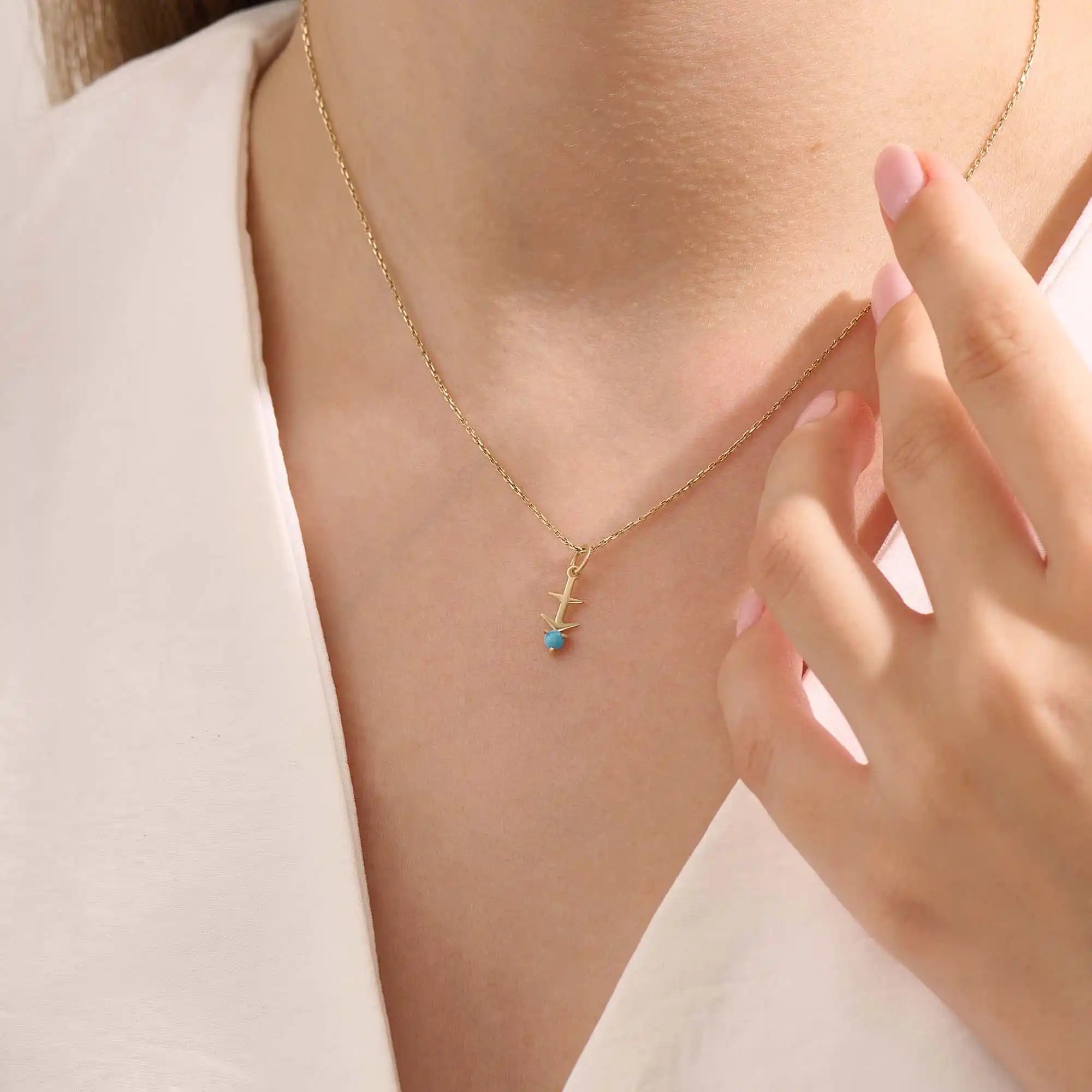 Model wears Sagittarius zodiac symbol pendant necklace in 14k solid gold with turquoise gemstone.