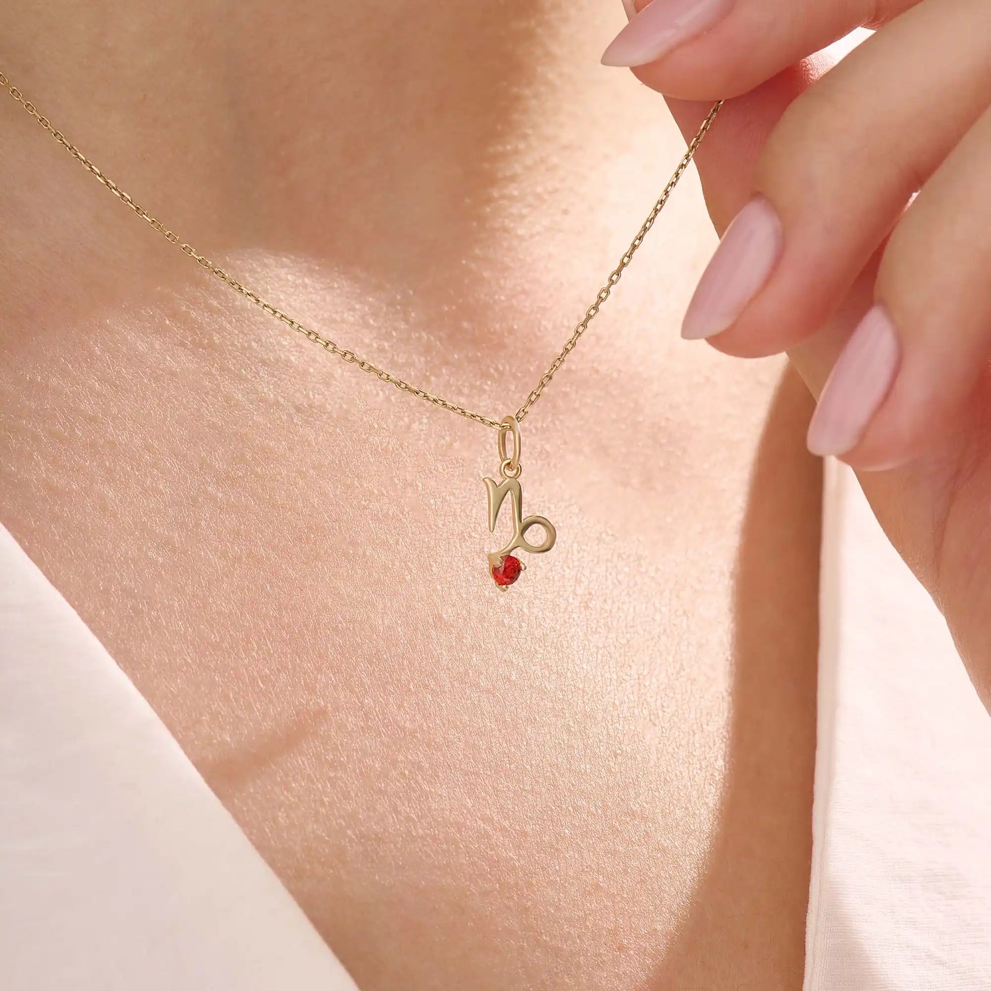 Model wears a 14k gold Capricorn zodiac necklace with a garnet birthstone accent. Elegant and symbolic jewelry for daily wear.