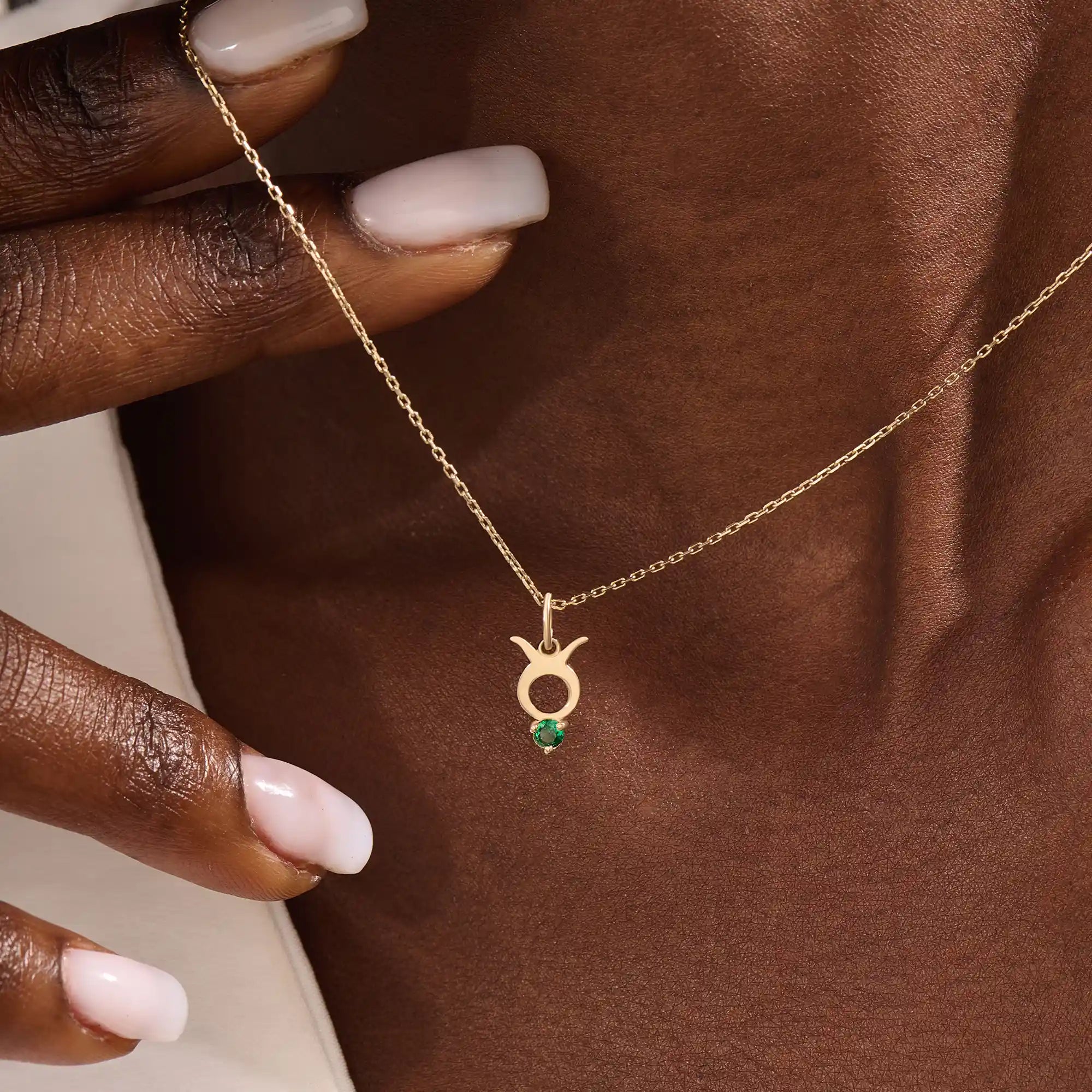 Model wears a 14k gold Taurus symbol necklace featuring an emerald stone. Stylish and meaningful for everyday wear or special gifts.