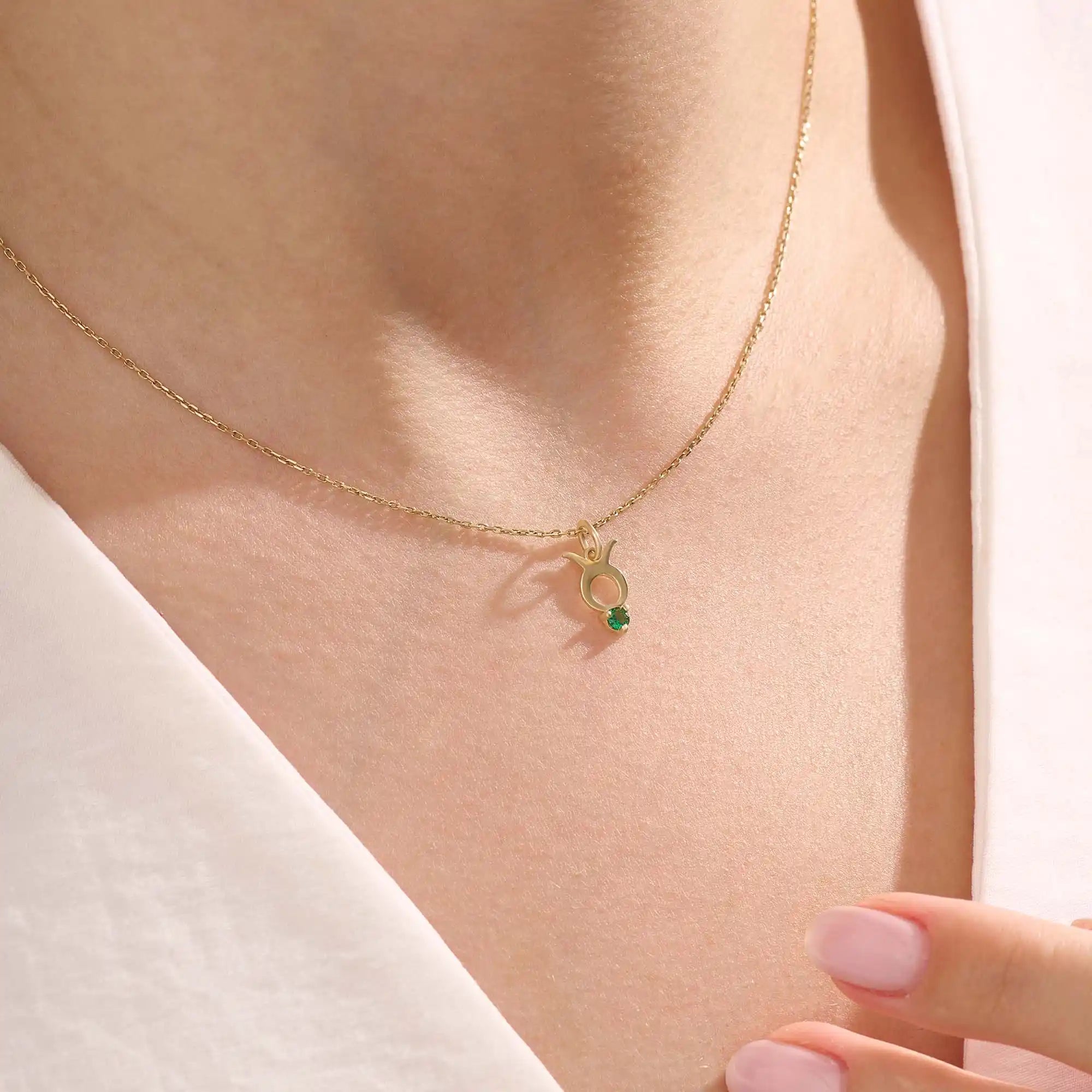 Model wears a 14k gold Taurus symbol necklace featuring an emerald stone. Stylish and meaningful for everyday wear or special gifts.