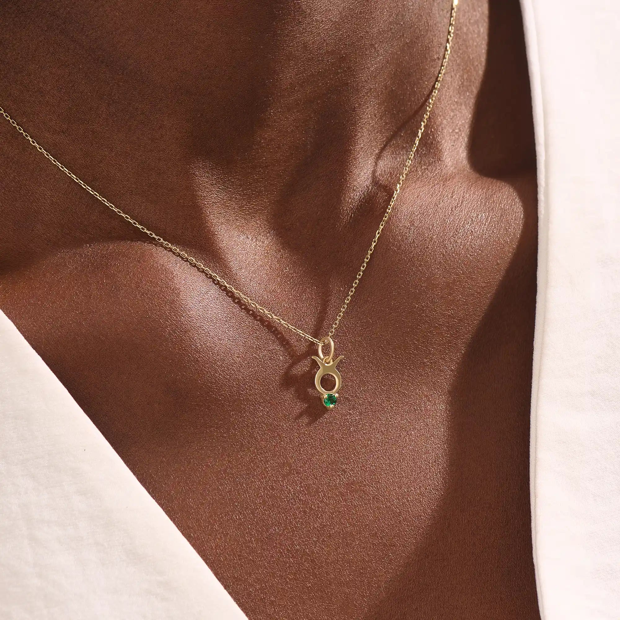 Model wears a 14k gold Taurus symbol necklace featuring an emerald stone. Stylish and meaningful for everyday wear or special gifts.