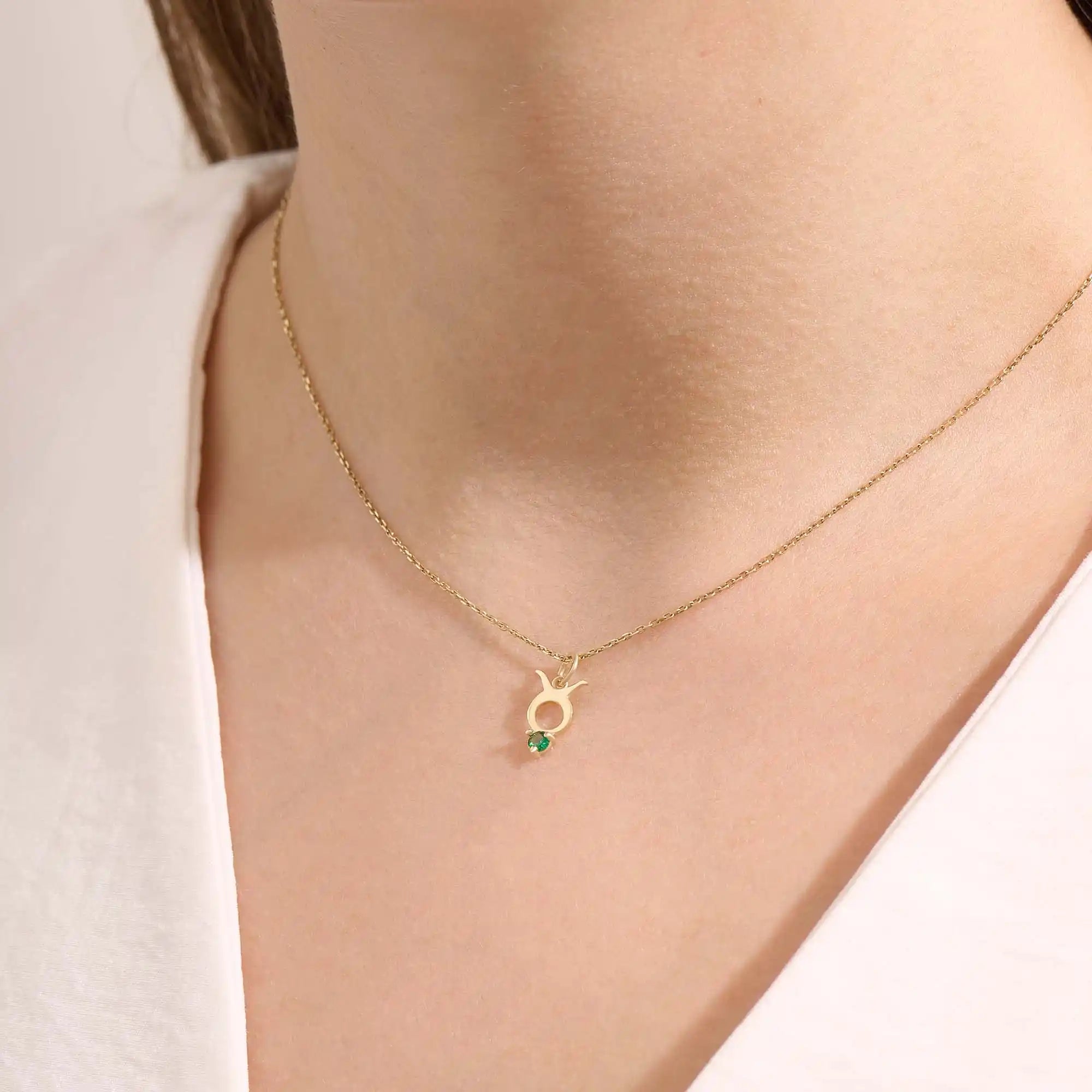Model wears a 14k gold Taurus symbol necklace featuring an emerald stone. Stylish and meaningful for everyday wear or special gifts.