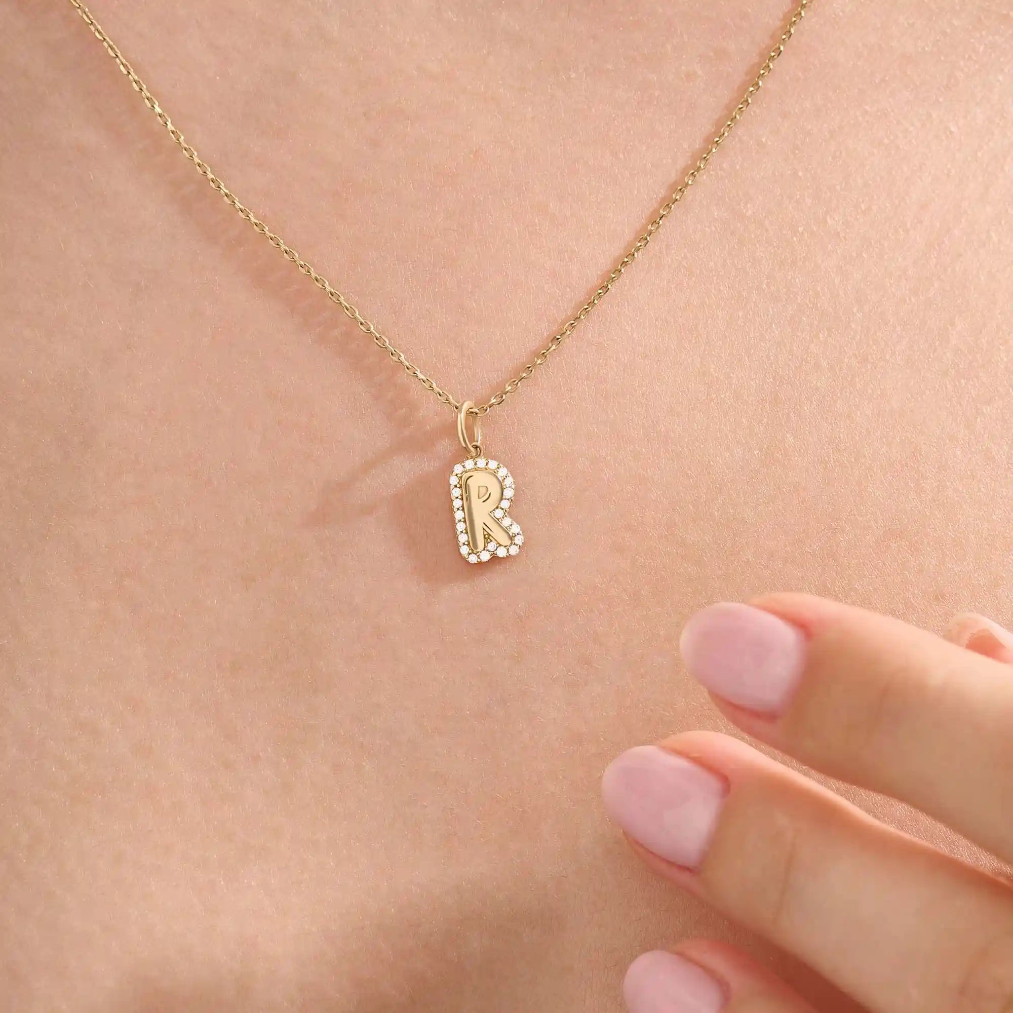 Model wears a 14k gold bubble initial necklace outlined with sparkling moissanites. Eye-catching and stylish, perfect for daily wear.