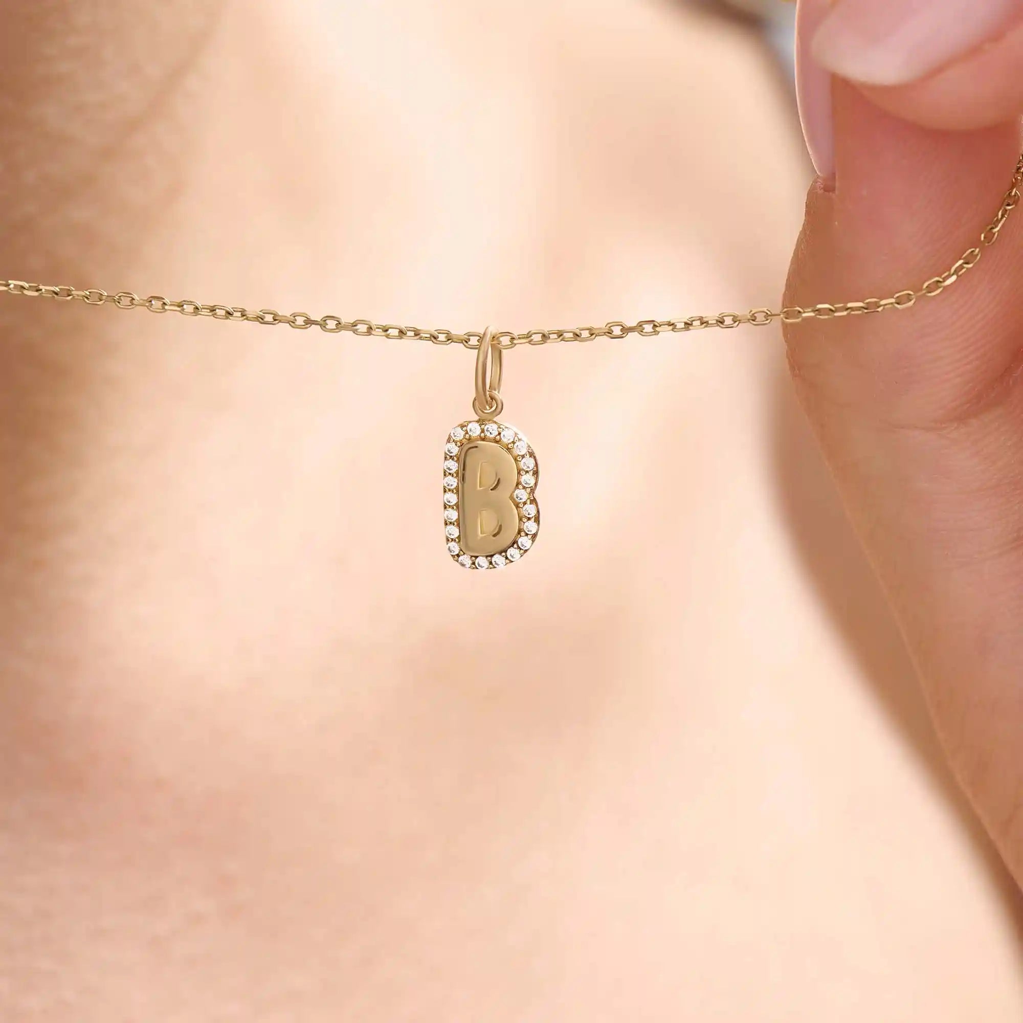 Model wears a 14k gold bubble initial necklace outlined with sparkling moissanites. Eye-catching and stylish, perfect for daily wear.