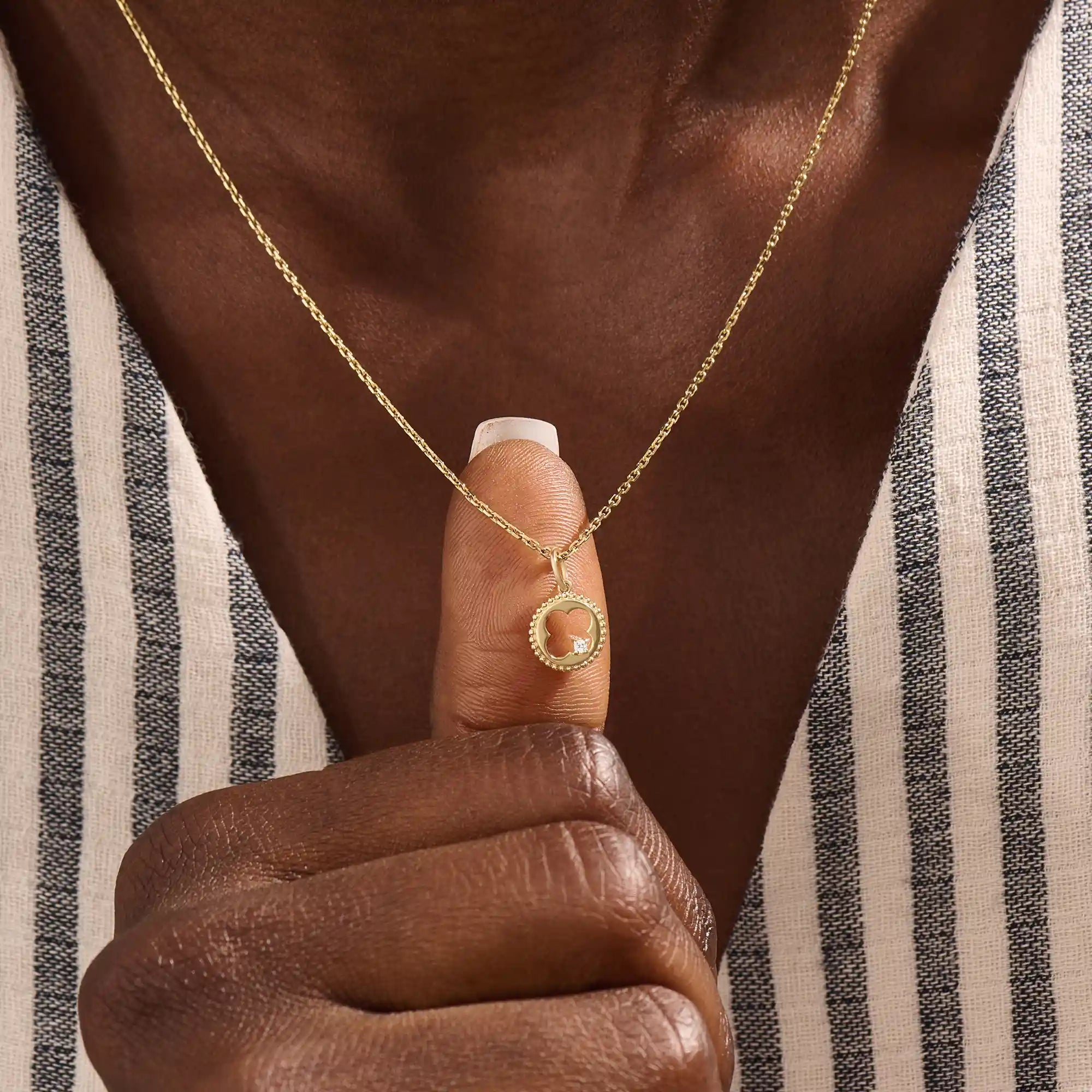 Model wears a 14k gold circle pendant necklace with clover cutout and single moissanite accent. A minimalist and meaningful everyday accessory.