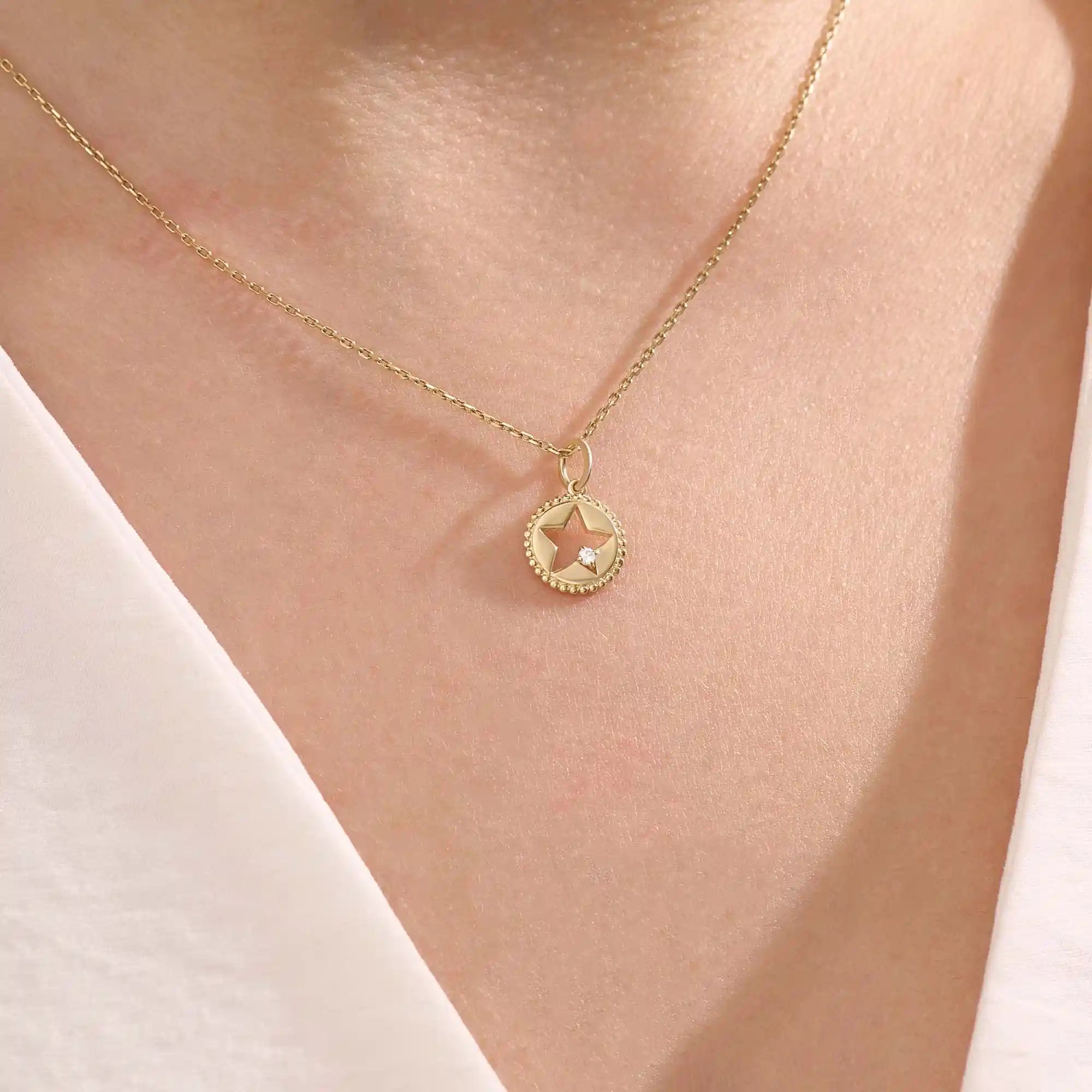 Model wears a 14k gold circle pendant necklace with star cutout and single moissanite accent. A minimalist and elegant everyday jewelry piece.