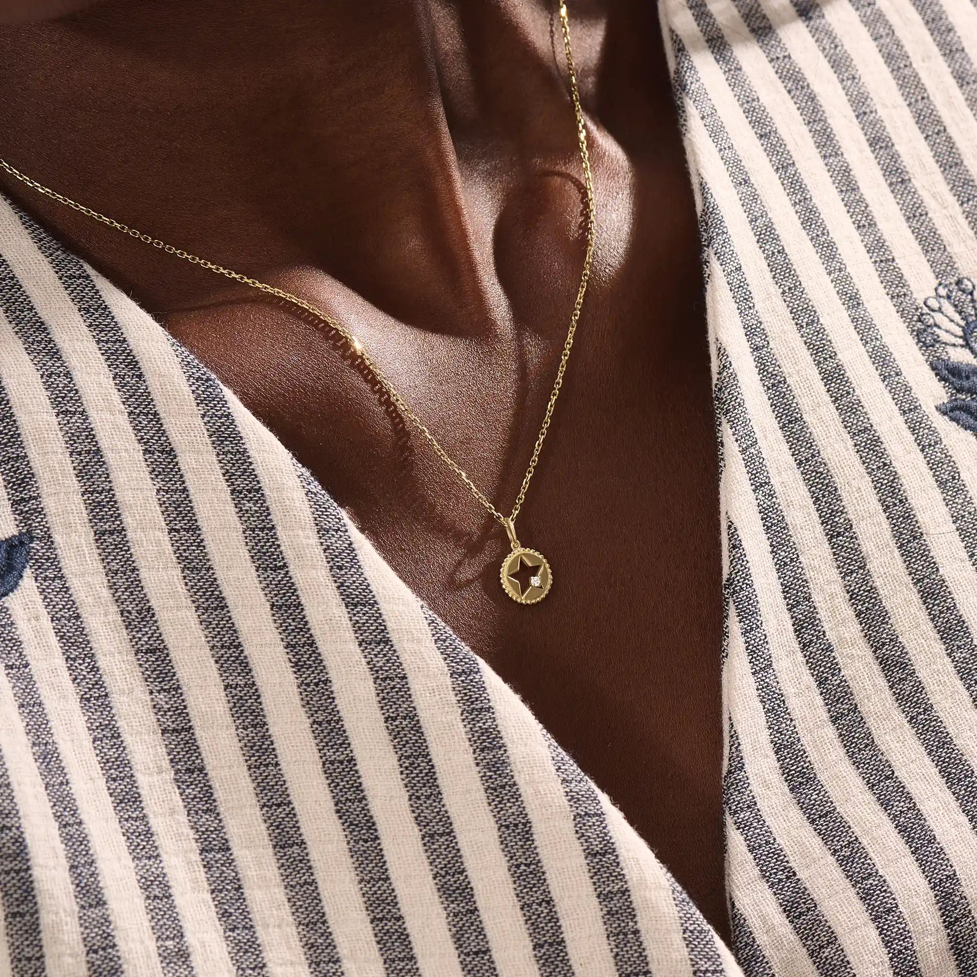 Model wears a 14k gold circle pendant necklace with star cutout and single moissanite accent. A minimalist and elegant everyday jewelry piece.