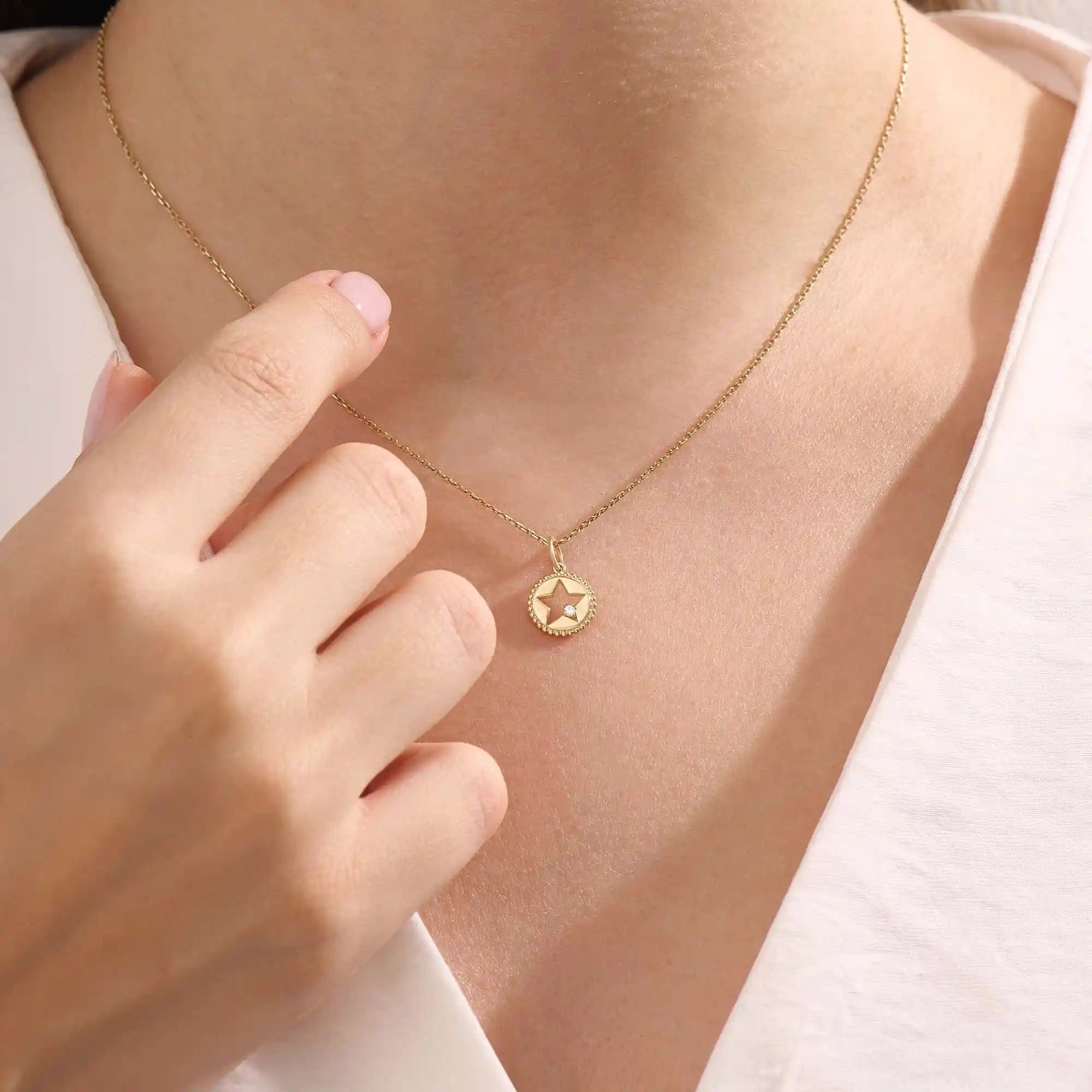 Model wears a 14k gold circle pendant necklace with star cutout and single moissanite accent. A minimalist and elegant everyday jewelry piece.