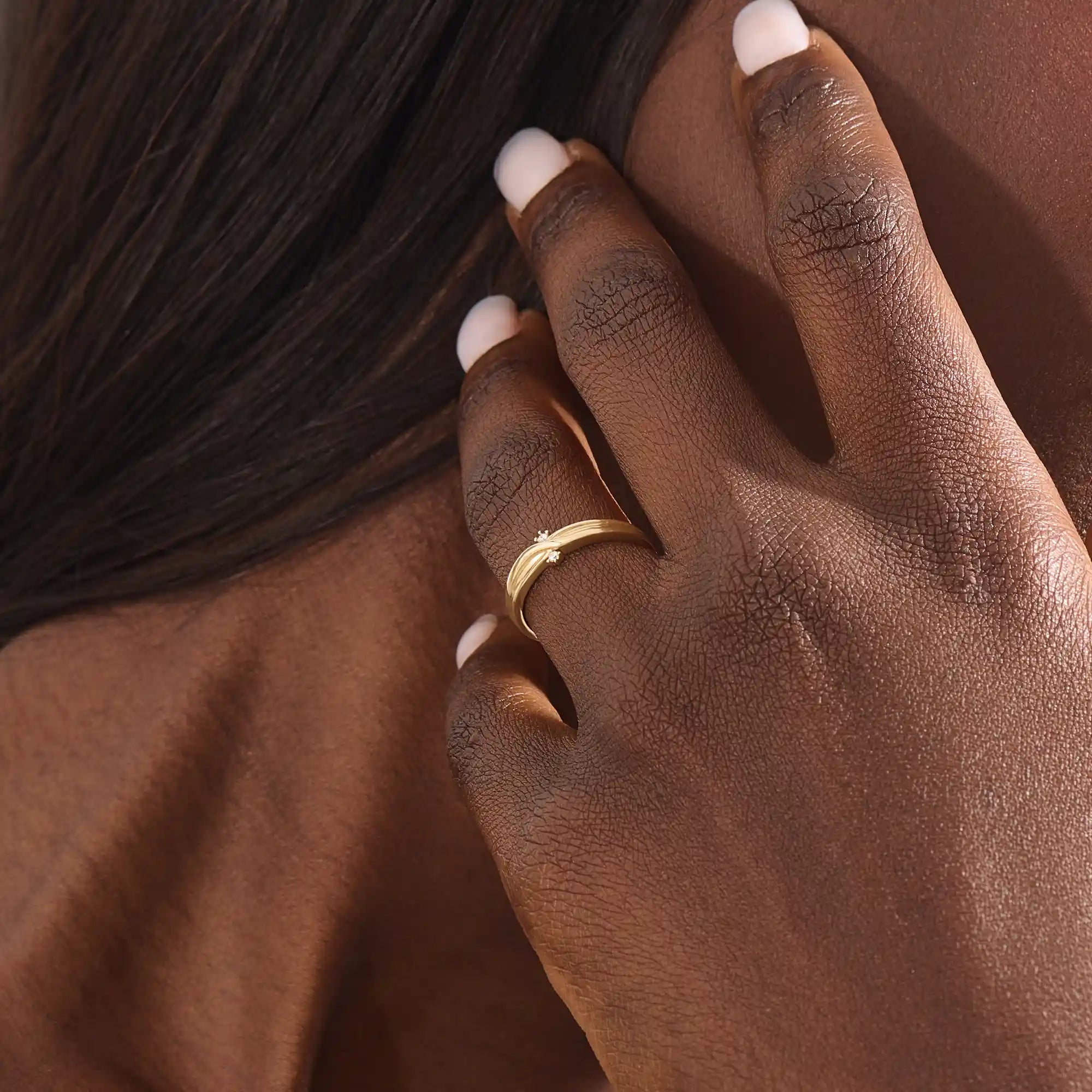 Model wears a 14k gold crossover band promise ring featuring delicate moissanite accents. A stylish and modern symbol of commitment.