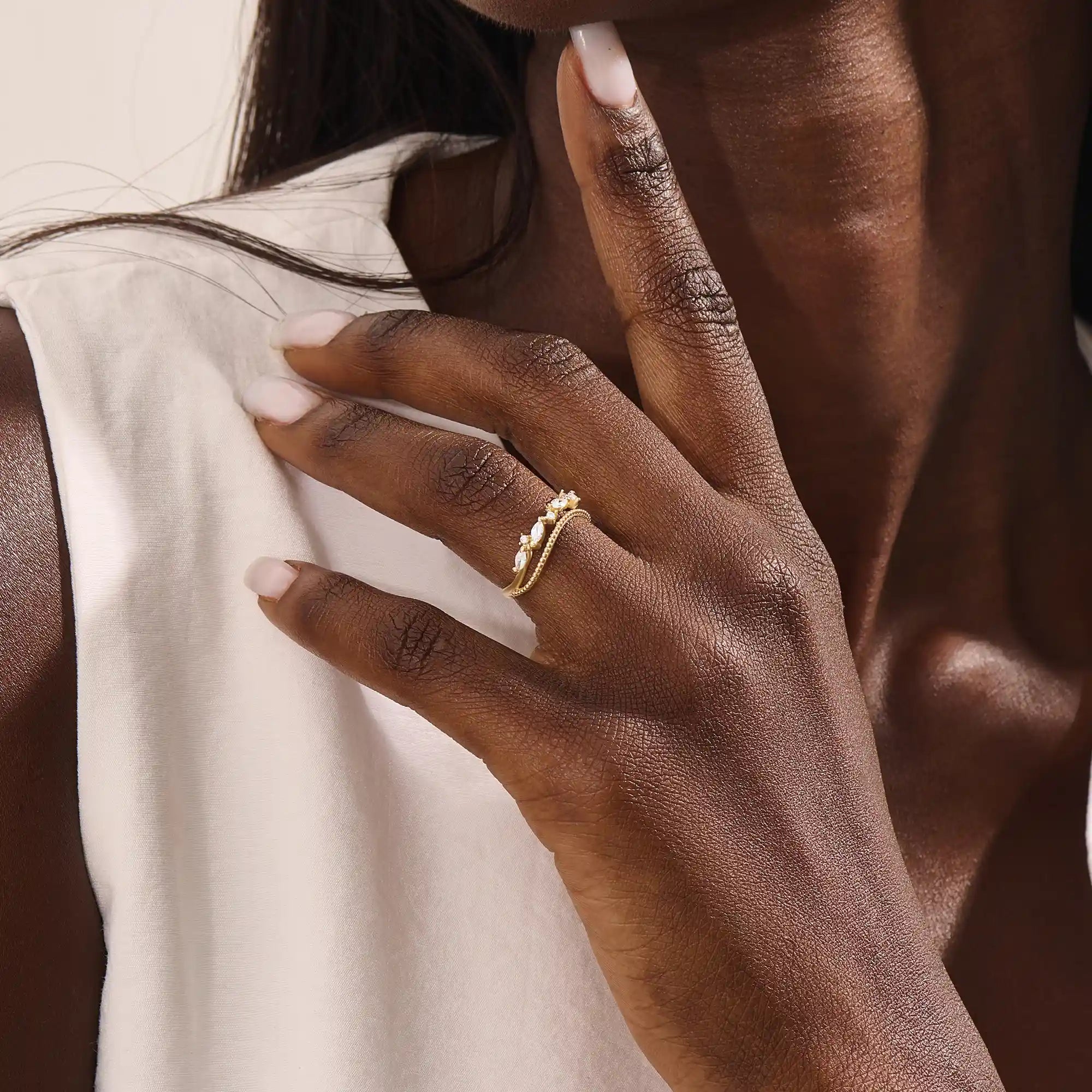 Model wears a 14k gold curved beaded ring adorned with round and marquise moissanites. An eye-catching stackable ring with elegant sparkle.