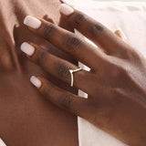 Model wears a 14k gold curved ring featuring a triangle moissanite centerpiece and pavé accents. Perfect for stacking with solitaires or bands.