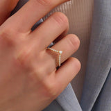 Model wears a 14k gold curved ring featuring a triangle moissanite centerpiece and pavé accents. Perfect for stacking with solitaires or bands.