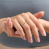 Model wears a 14k gold eternity band ring featuring small daisy flowers. Perfect for stacking or as a charming everyday statement piece